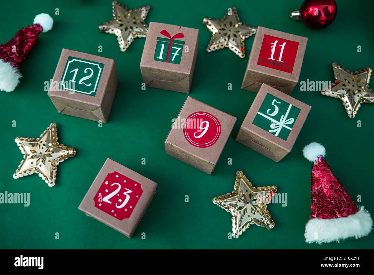 Calendario dell'Avvento fatto a mano: Crea cubetti di carta con numeri su uno sfondo verde lussureggiante. Festeggiamo la tradizione natalizia Foto Stock