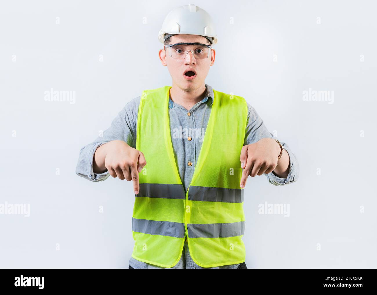 Ingegnere sorpreso che indichi lo spazio pubblicitario isolato. Stupito ingegnere maschio che indica uno spazio pubblicitario Foto Stock