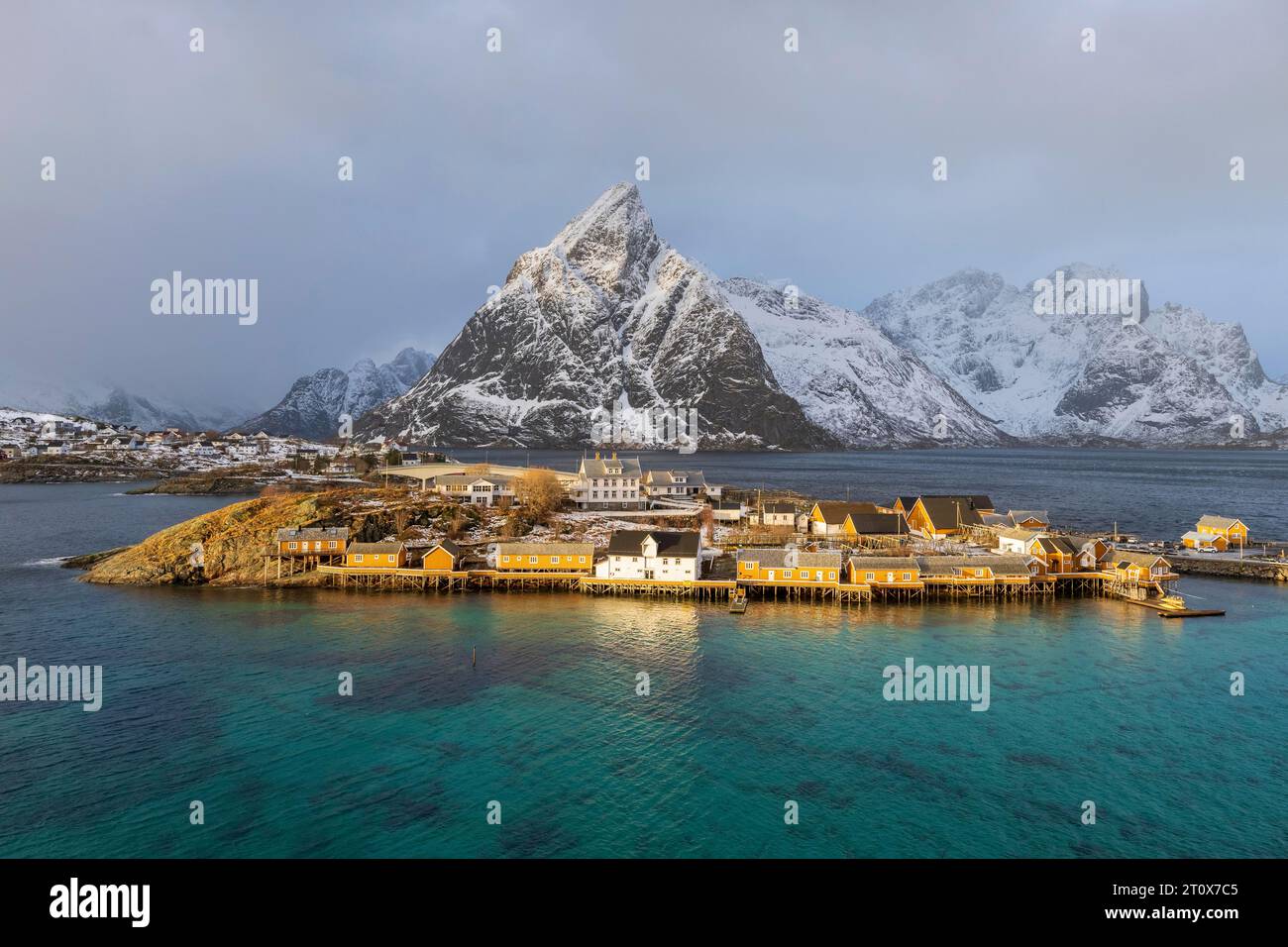 Cabine gialle tradizionali rorbuer sull'isola Sakrisoy, montagne rocciose innevate sul retro, Sakrisoy, Reine, Lofoten, Norvegia Foto Stock Cabine gialle tradizionali rorbuer sull'isola Sakrisoy, montagne rocciose innevate sul retro, Sakrisoy, Reine, Lofoten, Norvegia Foto Stock