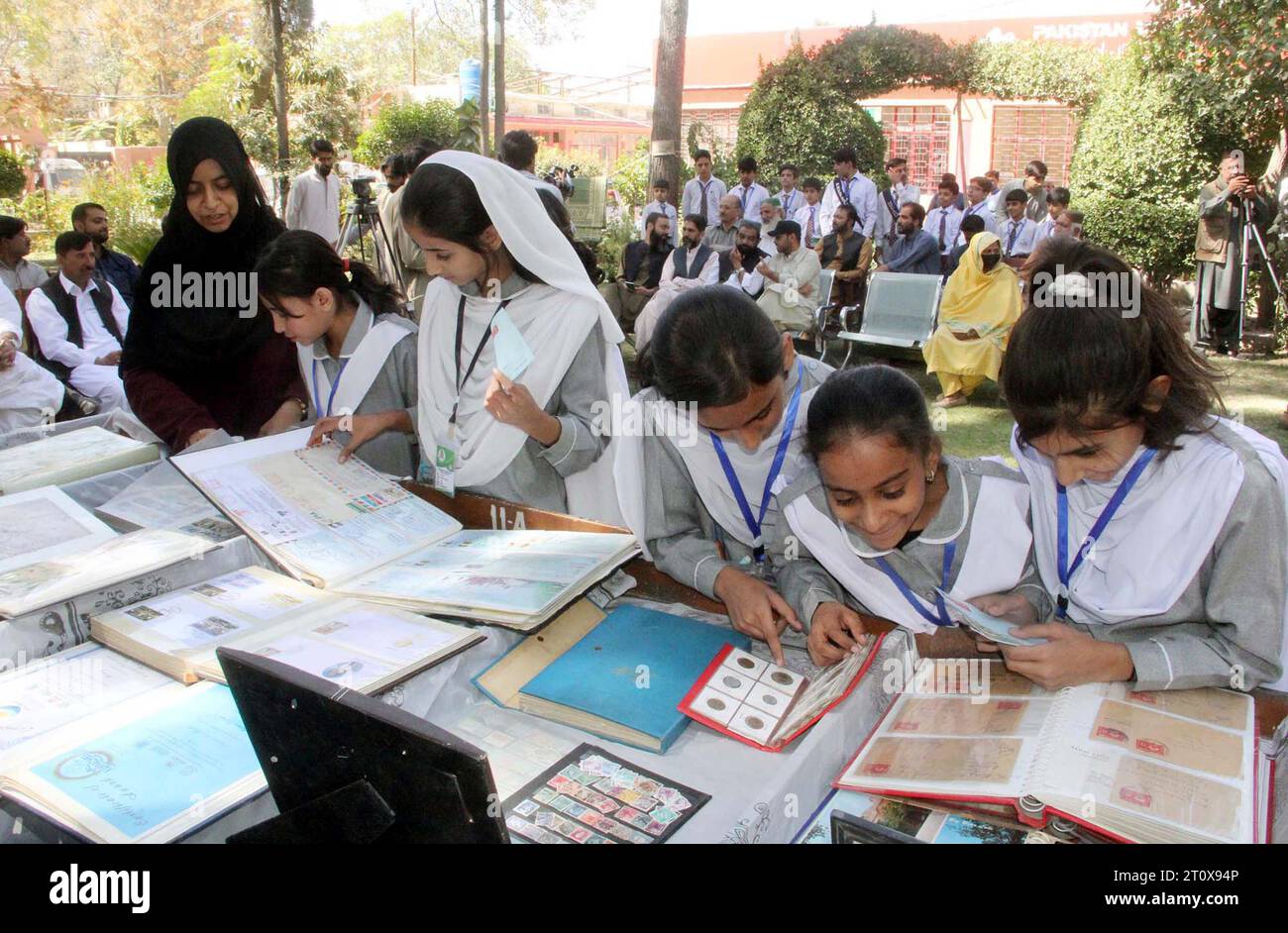 Gli studenti delle scuole si interessano molto ai vecchi francobolli durante la mostra in occasione della giornata internazionale della posta, tenutasi a Quetta lunedì 9 ottobre 2023. Foto Stock