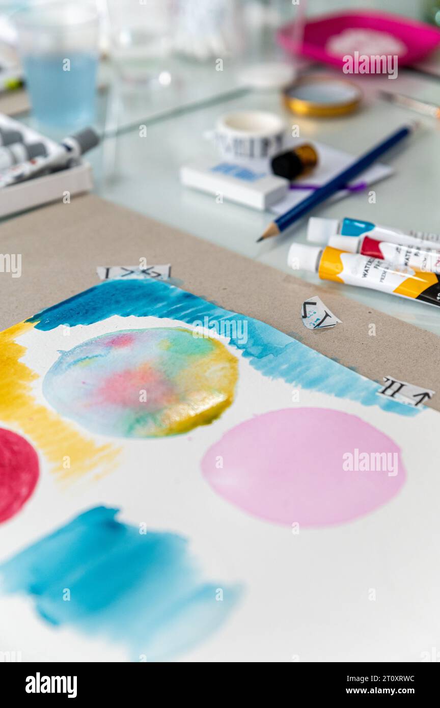Questa foto ravvicinata di un acquerello su un tavolo mostra un bellissimo e colorato design astratto. Il dipinto è pieno di colori vivaci. Foto Stock