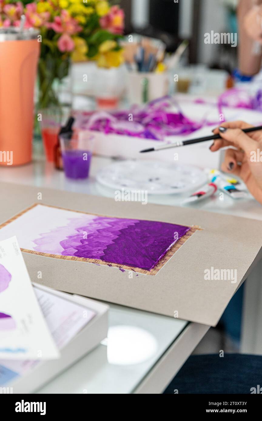 Questa foto ravvicinata di un acquerello su un tavolo mostra un bellissimo e colorato design astratto. Il dipinto è pieno di colori vivaci. Foto Stock