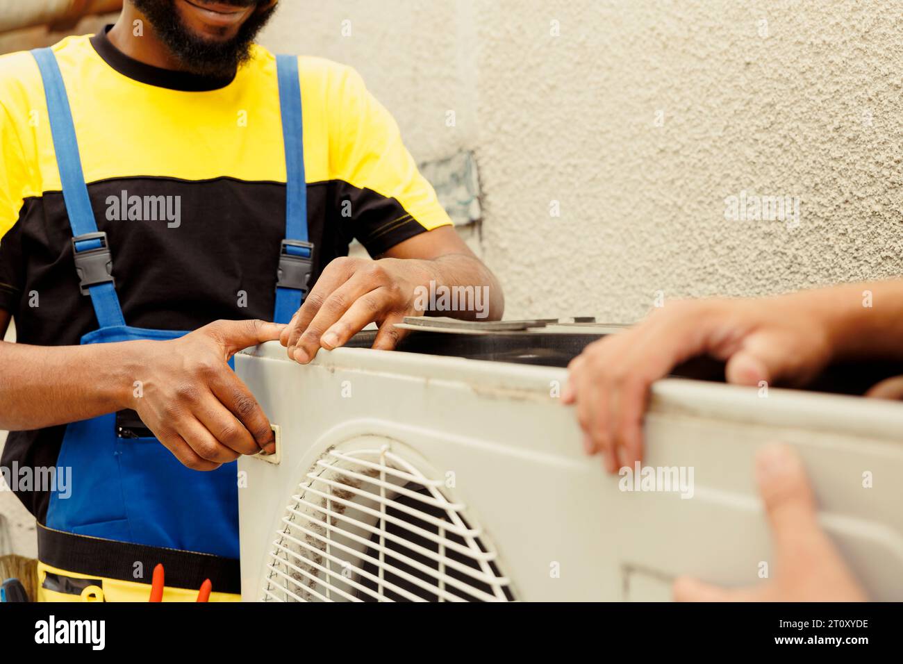 Un tecnico qualificato e un tecnico certificato che aprono il vecchio sistema hvac guasto per sostituirlo con un nuovo impianto di climatizzazione esterno dalle prestazioni elevate dopo aver scaricato il refrigerante e sostituito il condotto Foto Stock