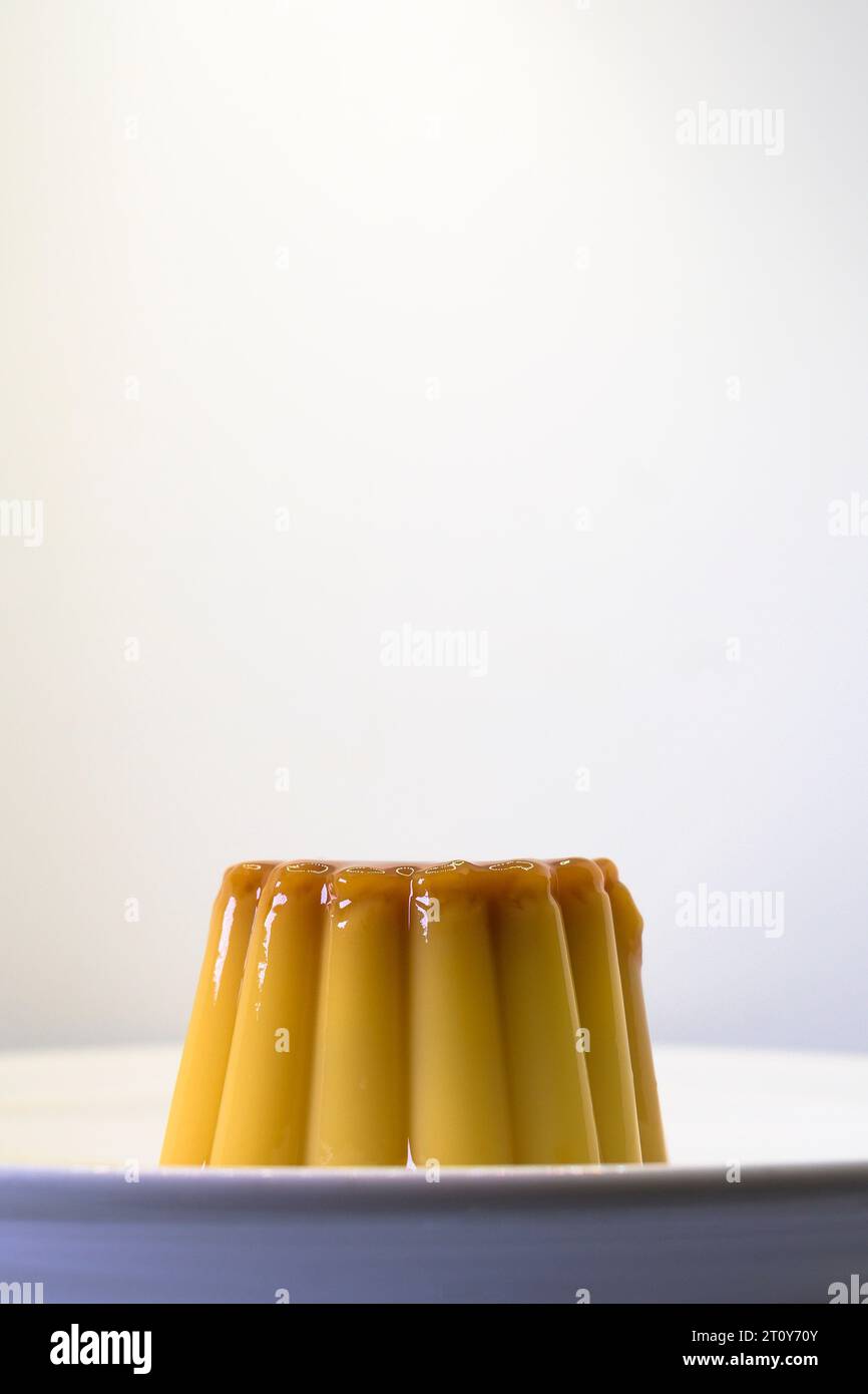 Dessert con crema pasticcera alla vaniglia e uova con caramello con sfondo bianco verticale Foto Stock