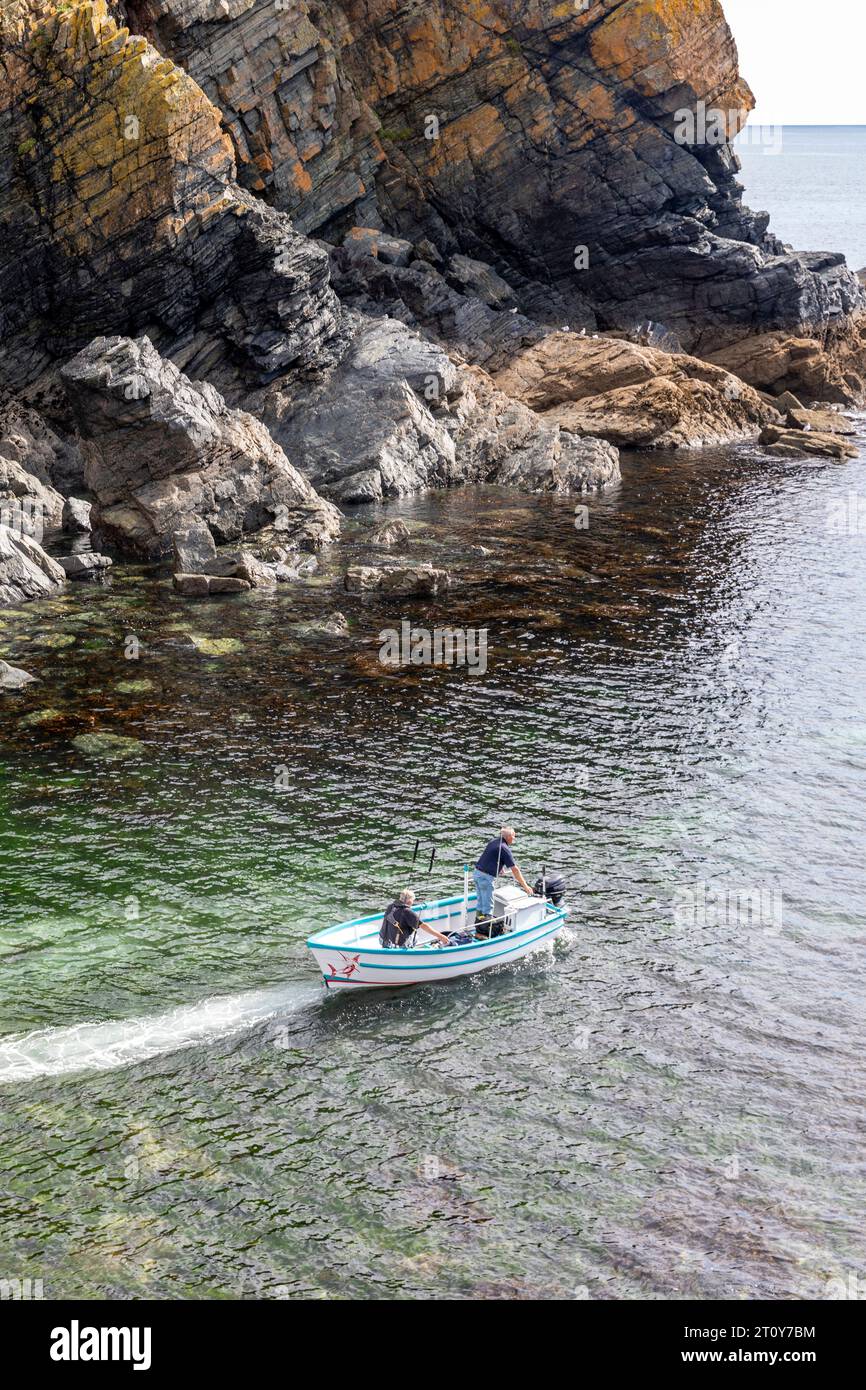 Cadgwith, villaggio sulla penisola di Lizard, Cornovaglia, pescatori inglesi in una piccola barca da pesca, lasciano l'insenatura Foto Stock