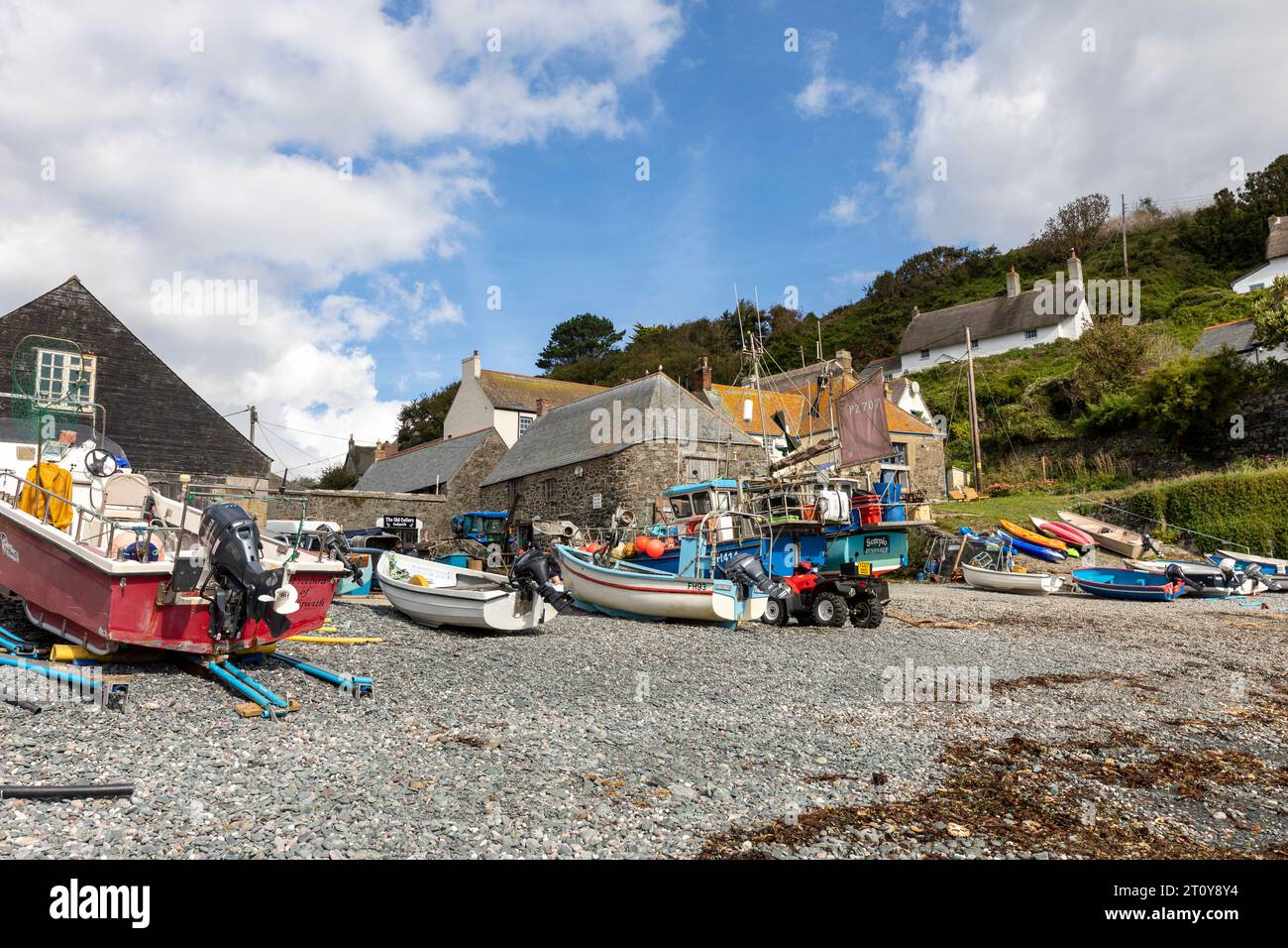 Cadgwith, villaggio sulla penisola di Lizard, Cornovaglia, Inghilterra, con barche da pesca e barche sulla spiaggia della baia Foto Stock