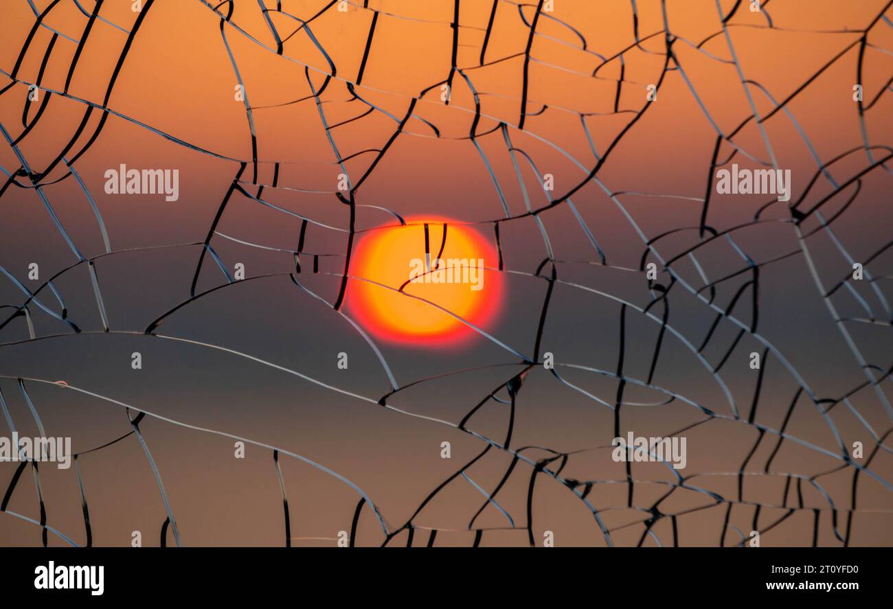 Sole attraverso il vetro incrinato al tramonto Foto Stock