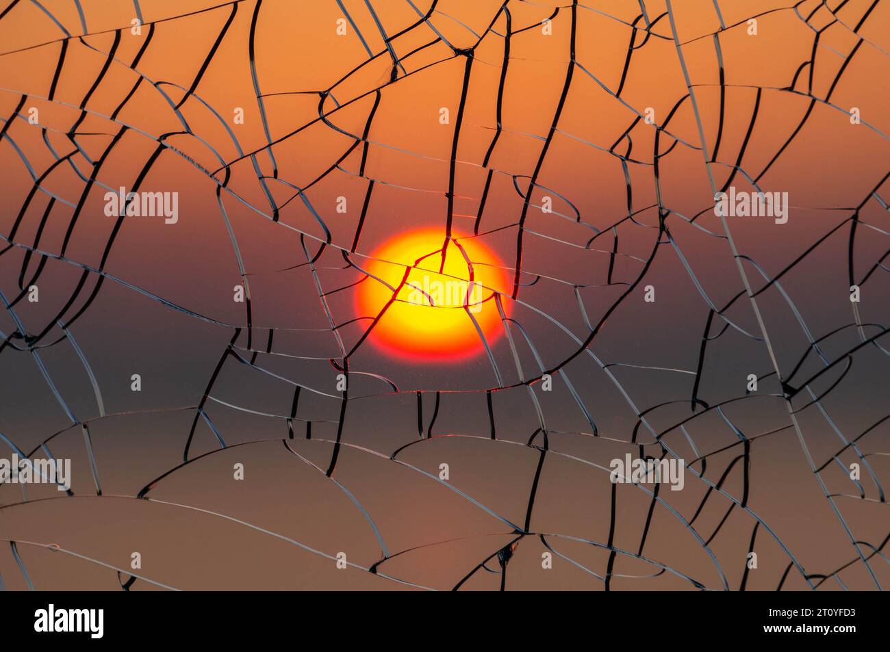 Sole attraverso il vetro incrinato al tramonto Foto Stock