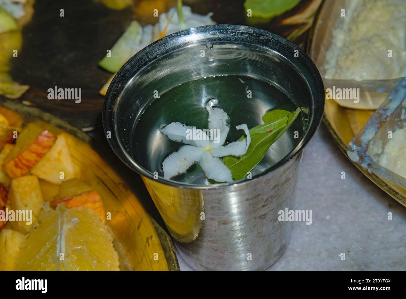 vetro in acciaio riempito con acqua e fiori per l'uso in occasione di puja Foto Stock