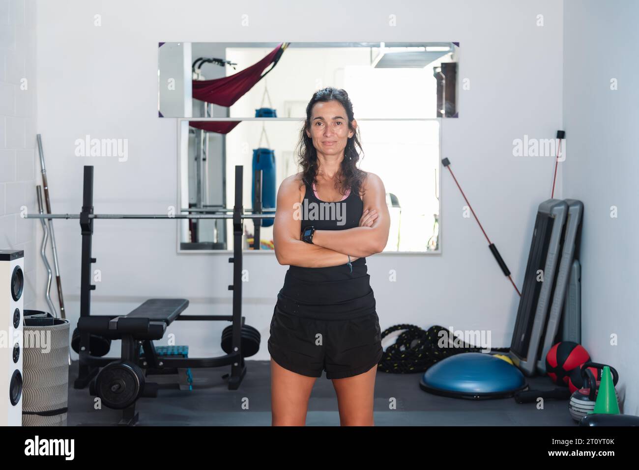 La personal trainer posa in un bel ritratto in palestra piena di macchine e attrezzature dove lavora Foto Stock