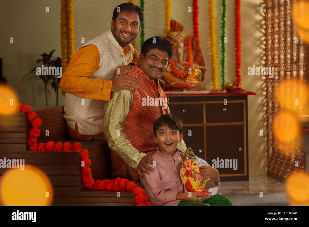 Ritratto di tre generazioni di una famiglia seduta su una scala, durante Ganesh Chaturthi una festa celebrata nel Maharashtra (India occidentale) Foto Stock