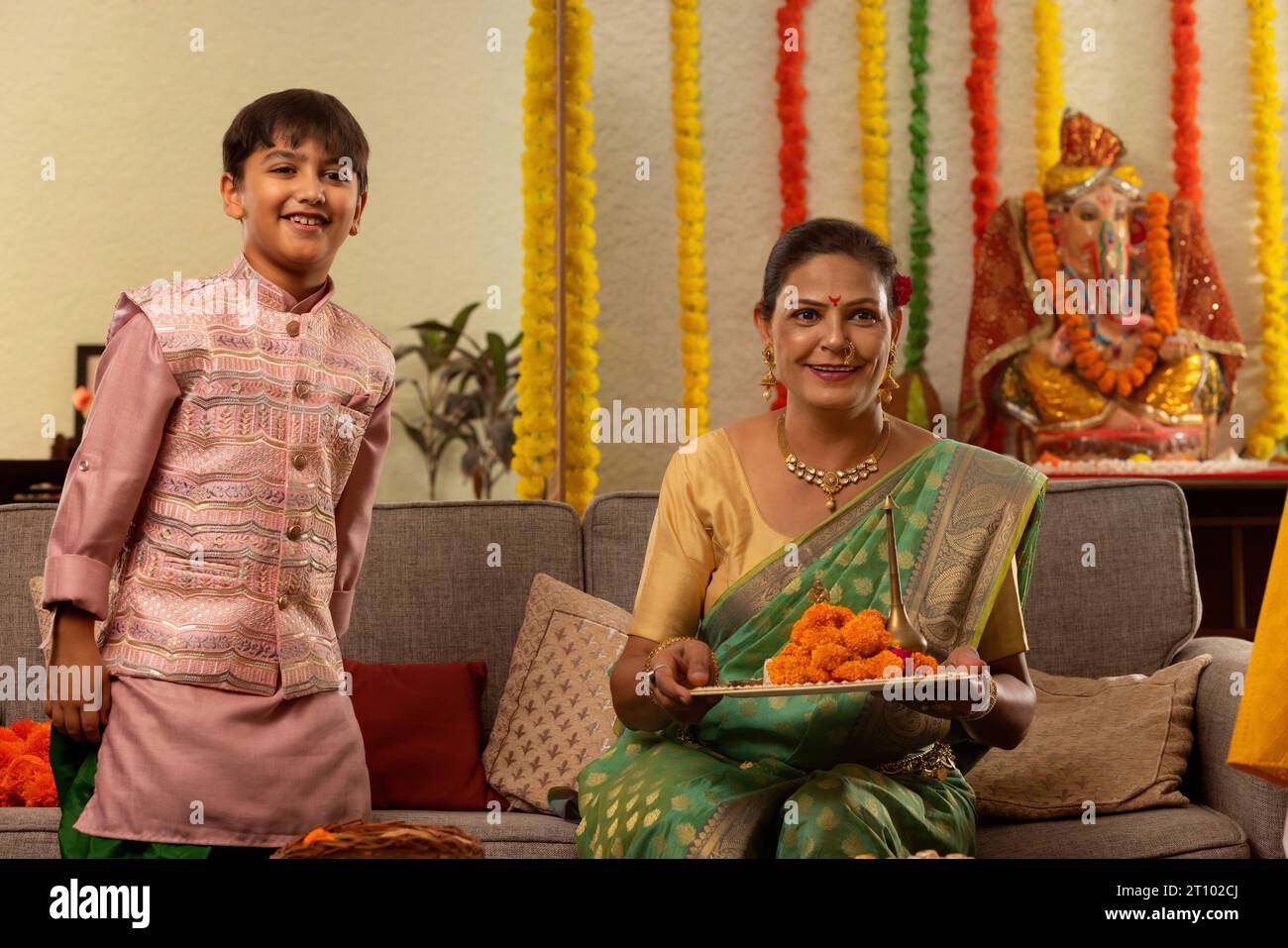 Donna maharashtriana che tiene una puja thali e suo nipote in piedi accanto Foto Stock