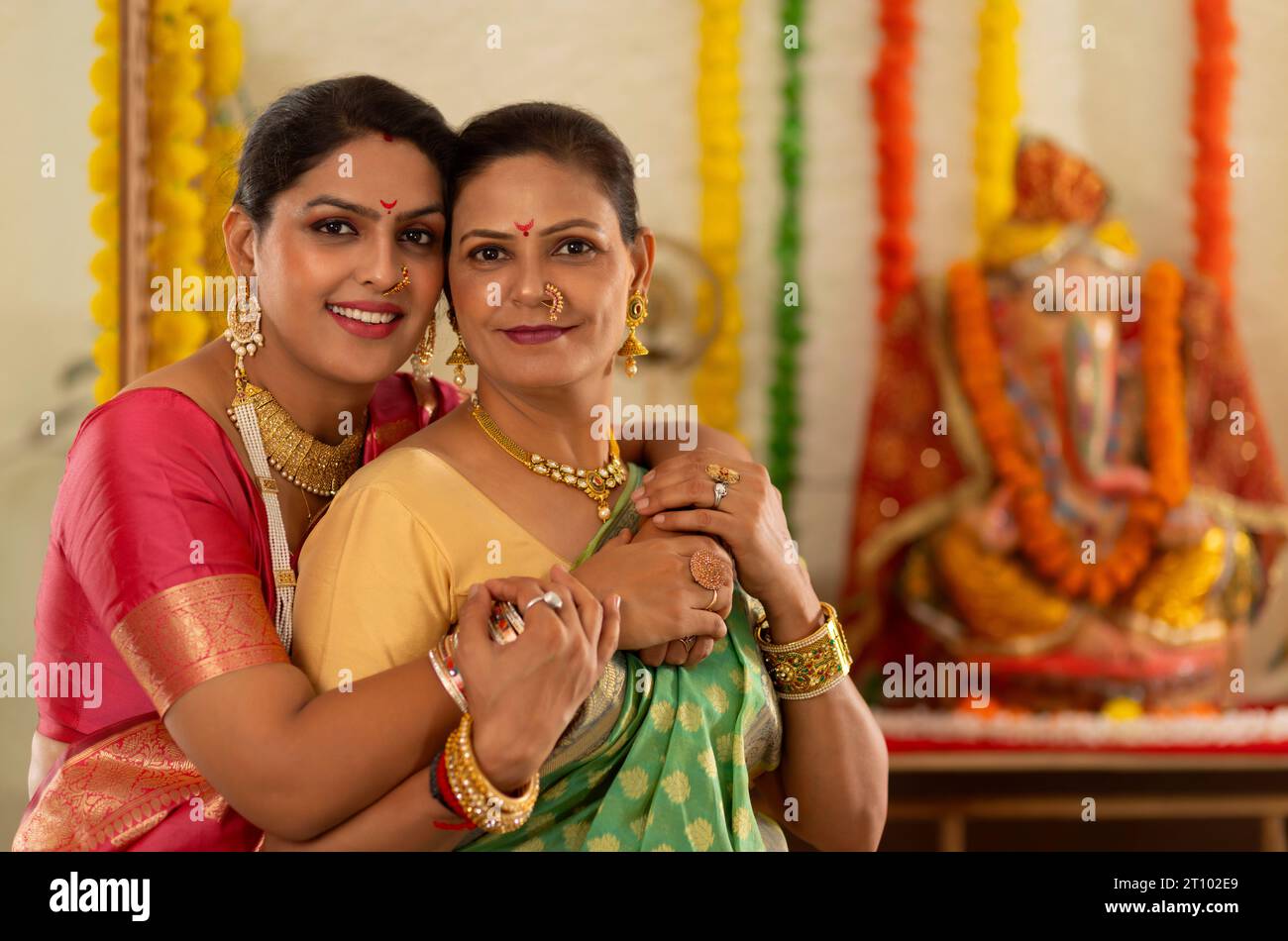 Nuora che abbraccia sua suocera di fronte all'idolo Ganesh Foto Stock