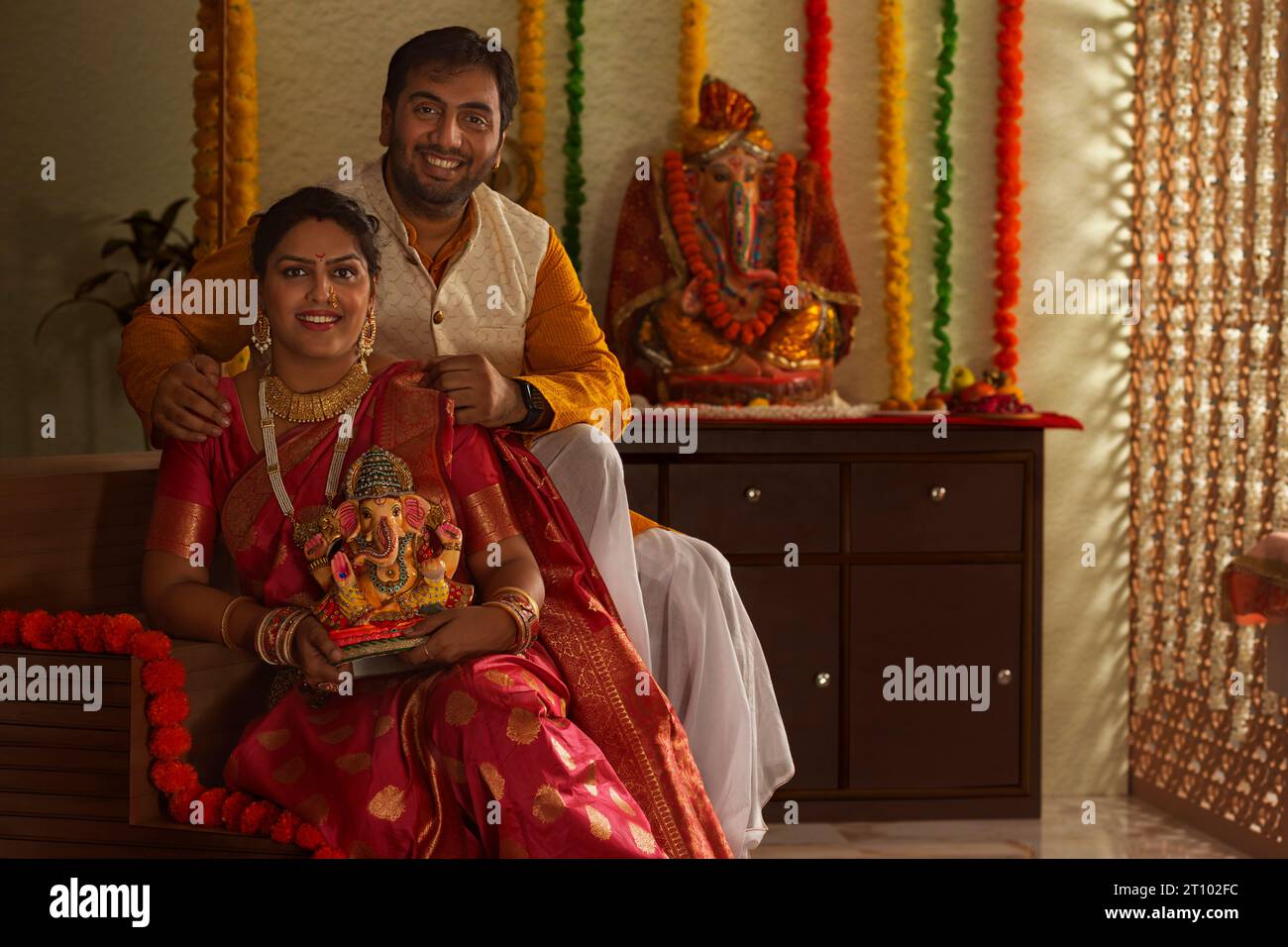 Giovane coppia maharashtrian che tiene in mano un idolo di Lord Ganesha mentre si siede insieme sulle scale Foto Stock