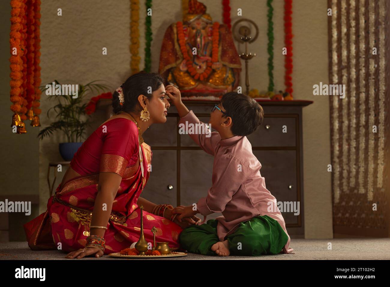 Figlio che applica tilaka alla fronte di sua madre in occasione di Ganesh Chaturthi Foto Stock