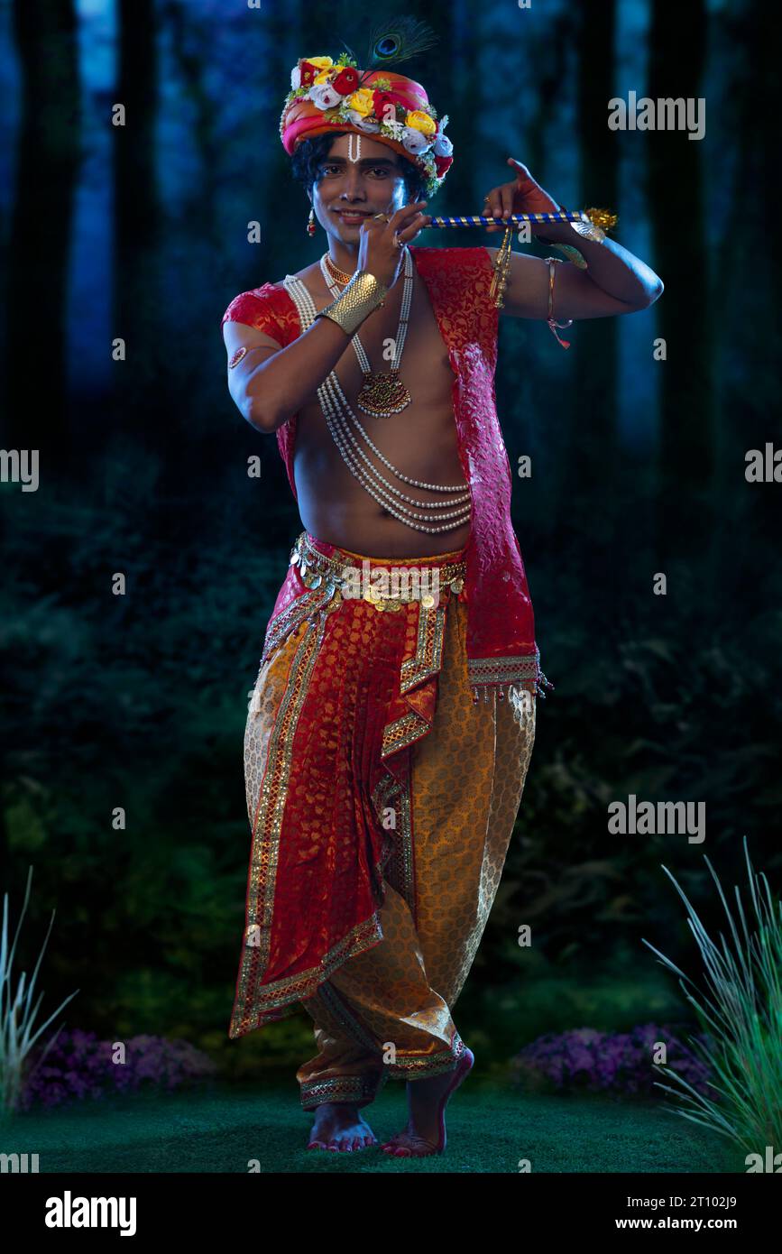 Giovane vestito da Lord Krishna e suonando il flauto in occasione di Janmashtami Foto Stock