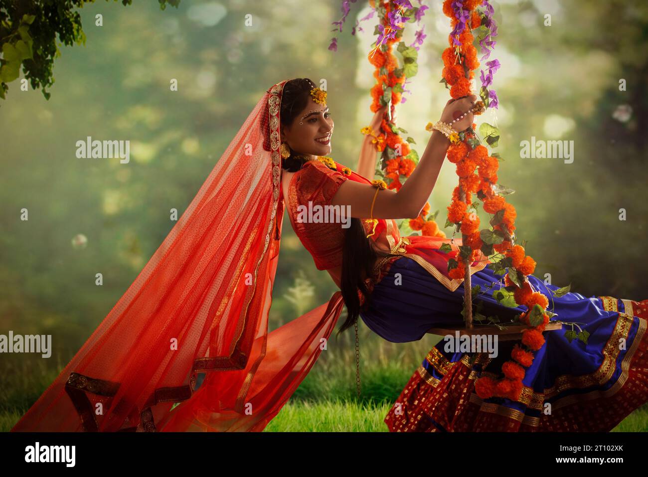 Giovane donna vestita da Radha e seduta su un altalena in occasione di Janmashtami Foto Stock