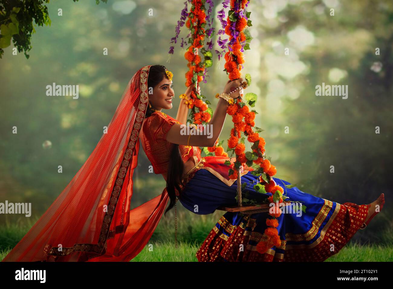 Giovane donna vestita da Radha e seduta su un altalena in occasione di Janmashtami Foto Stock