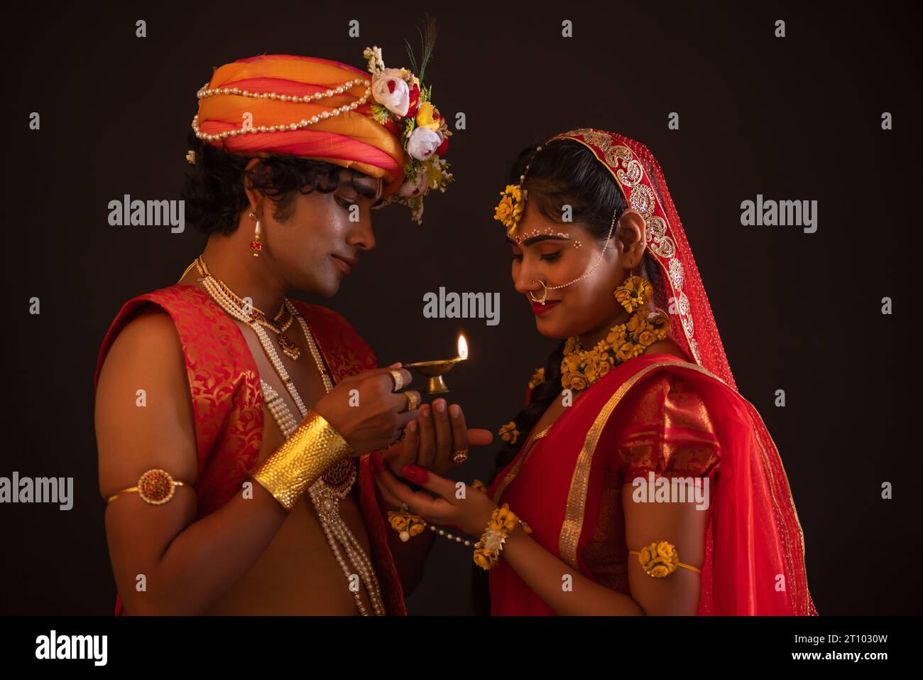 Giovane uomo e donna vestiti come Lord Radha e Krishna e tenendo diya insieme in occasione di Janmashtami Foto Stock