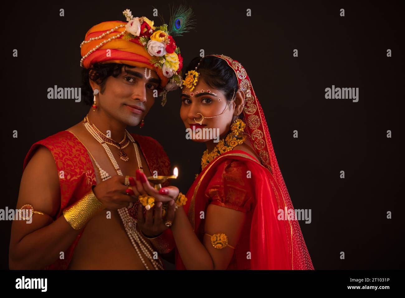 Giovane uomo e donna vestiti come Lord Radha e Krishna e tenendo diya insieme in occasione di Janmashtami Foto Stock