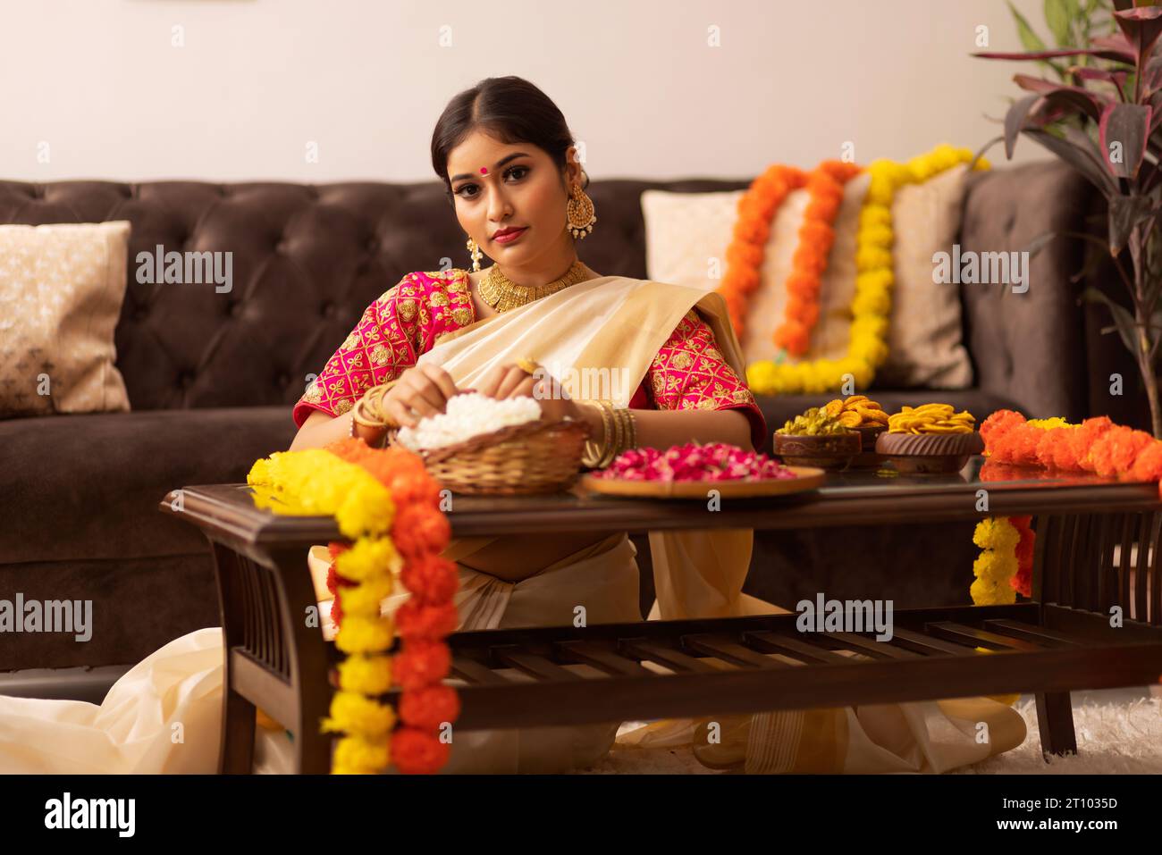 Donna dell'India meridionale con fiori di garlanding sari bianchi per celebrare l'Onam Foto Stock