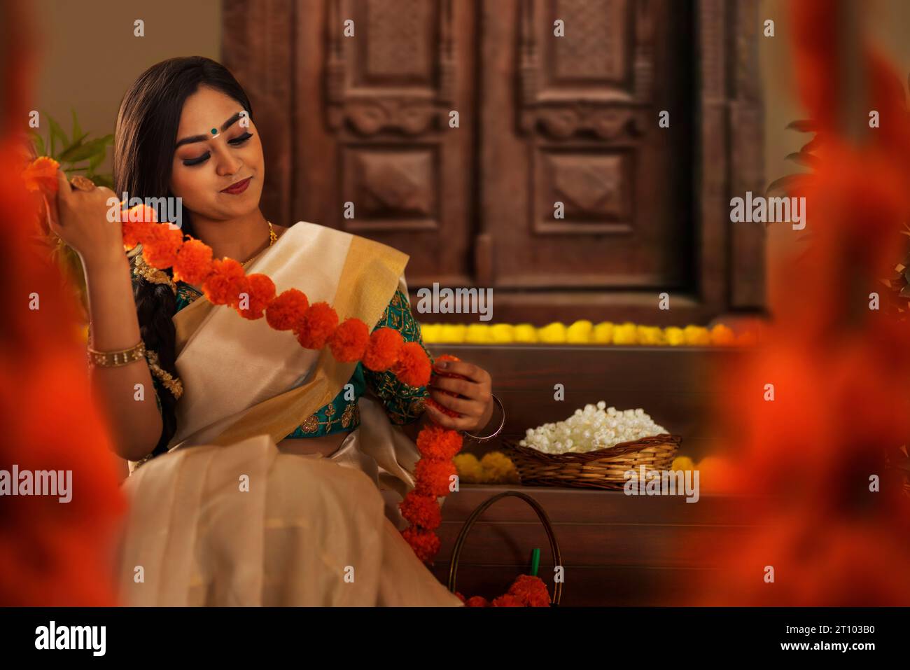 Donna con fiori di garlanding sari bianchi per celebrare l'Onam Foto Stock