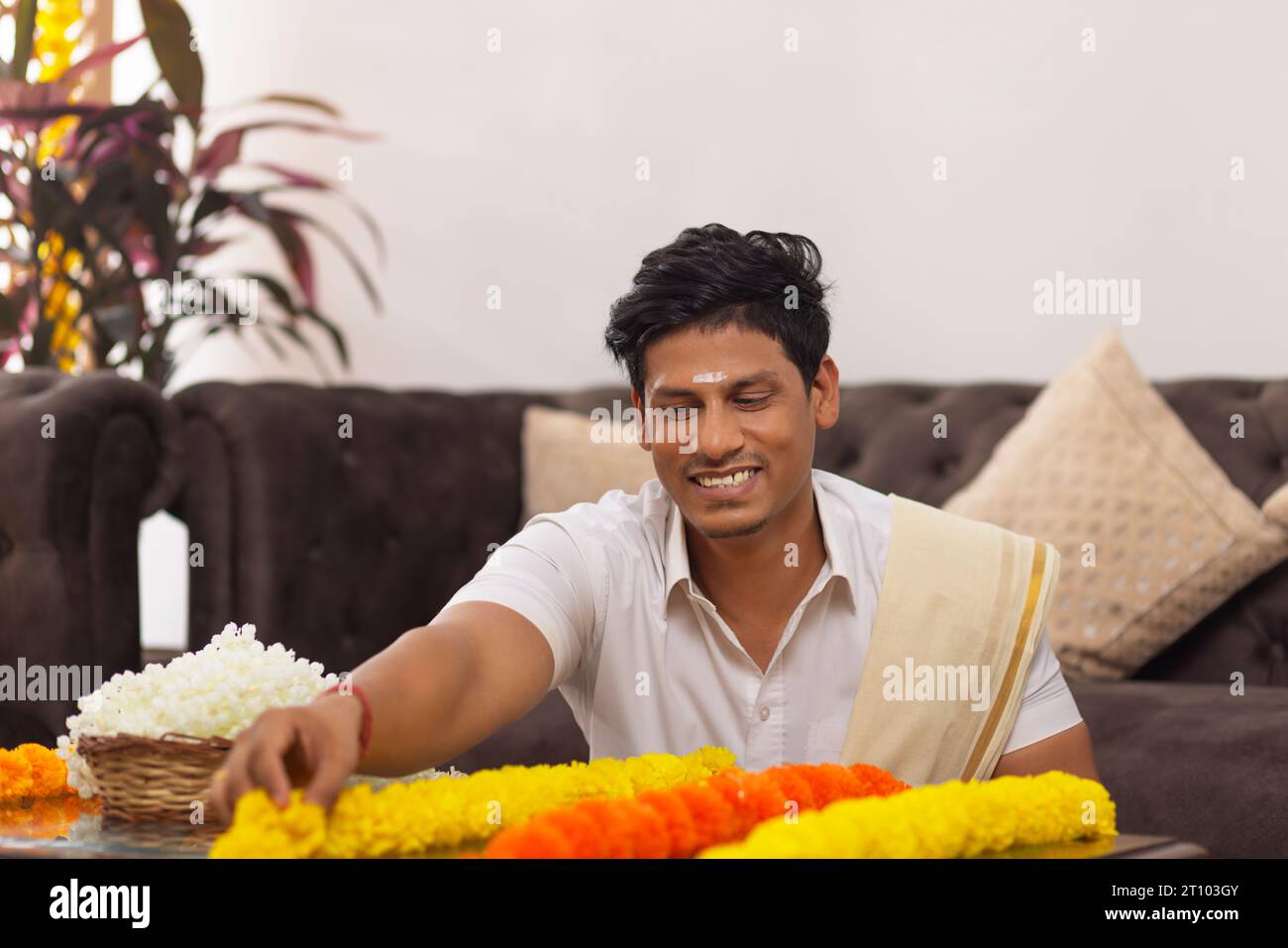 Uomo dell'India meridionale con camicia bianca e fiori da ghirlando per celebrare l'Onam Foto Stock