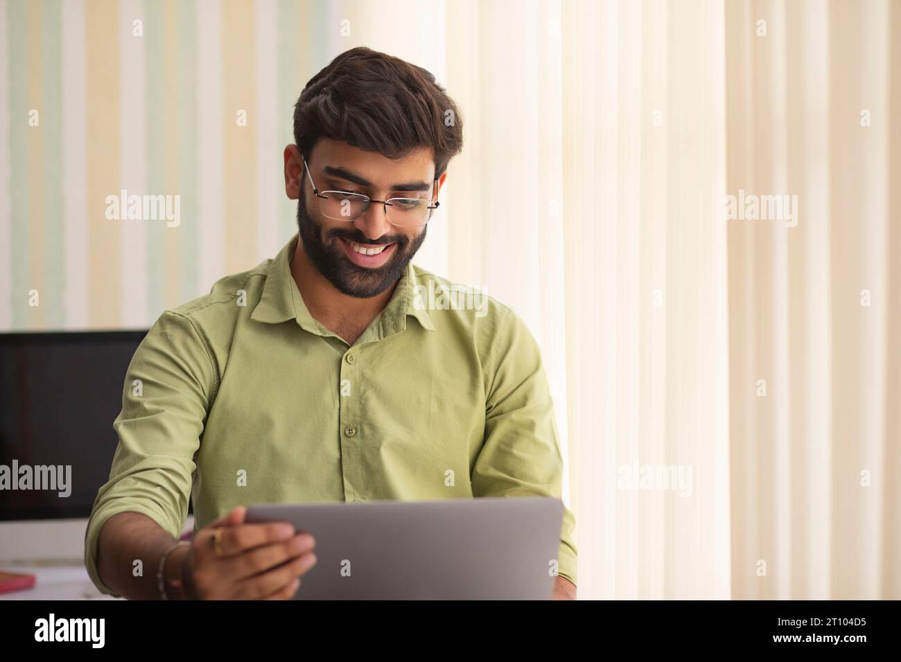 Un giovane che lavora con un computer portatile nel suo ufficio domestico Foto Stock