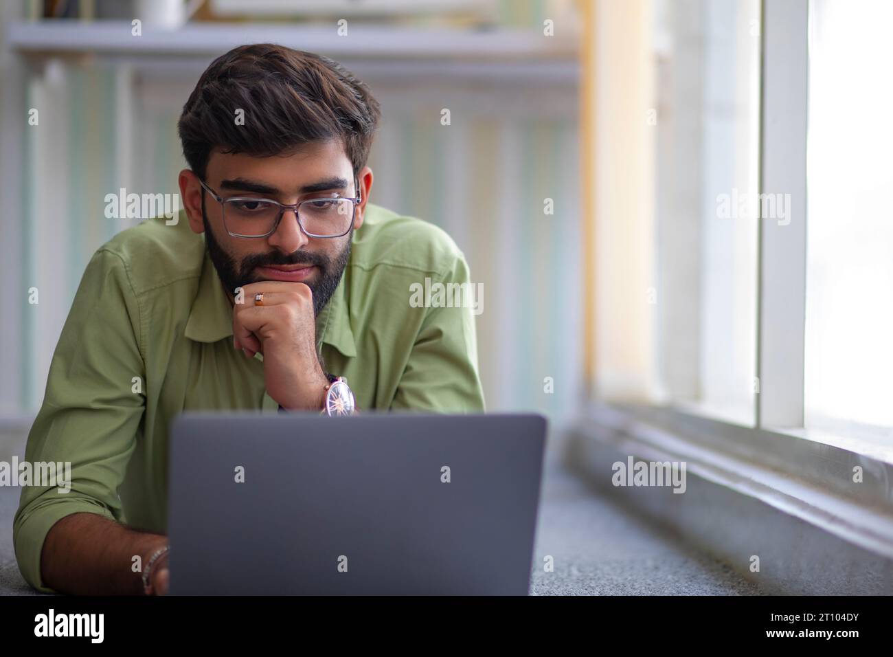 Un giovane che lavora con un computer portatile nel suo ufficio domestico Foto Stock