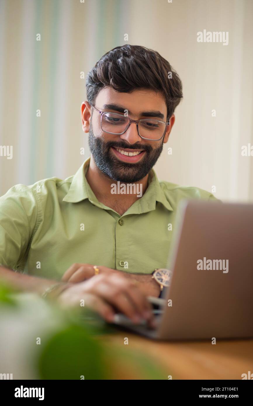 Ritratto ravvicinato di un giovane che lavora con un notebook nel suo ufficio domestico Foto Stock