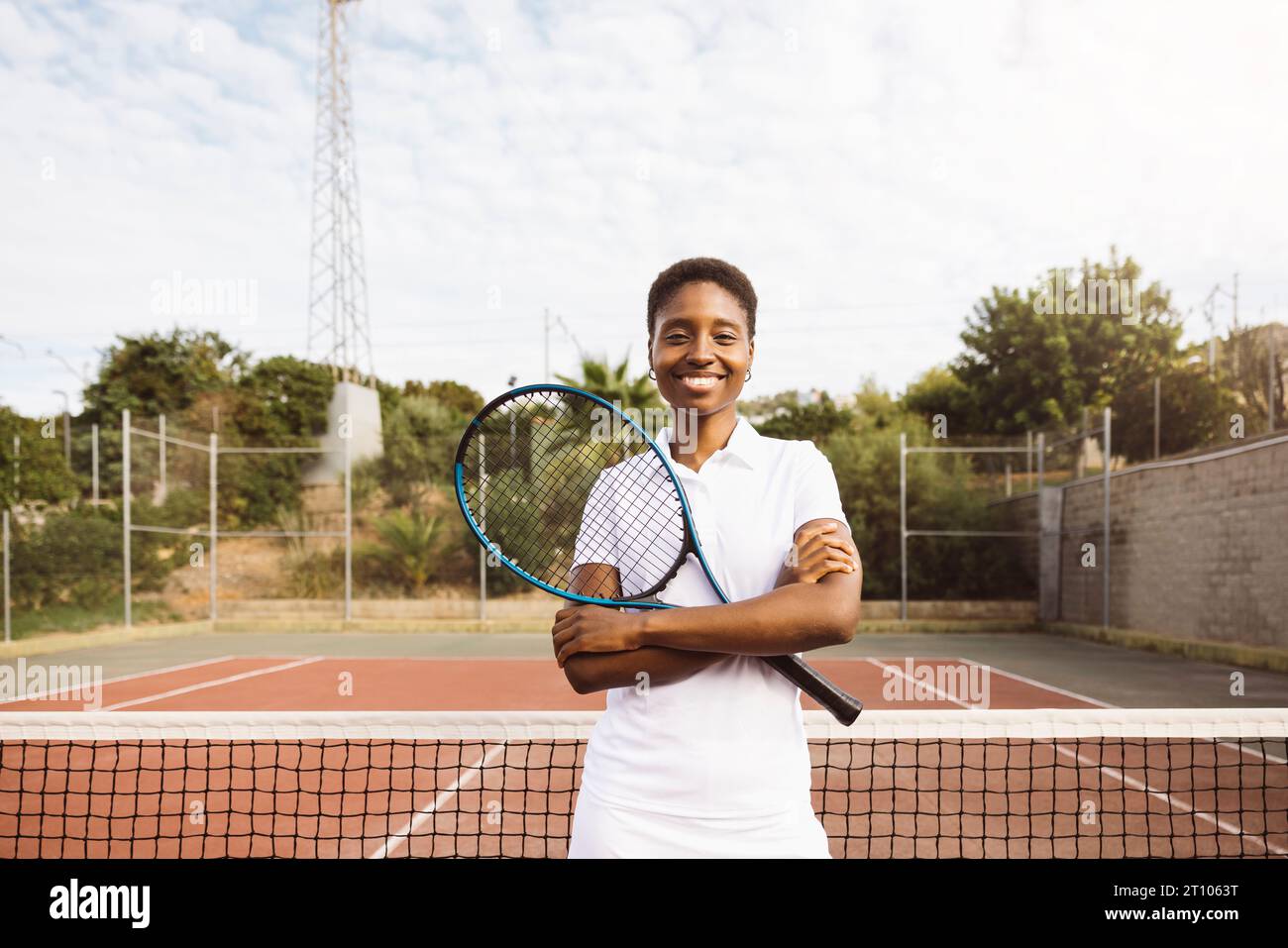 Ritratto di una giovane bella donna con vestiti da tennis e racchetta in un campo da tennis pronto a giocare. Foto Stock