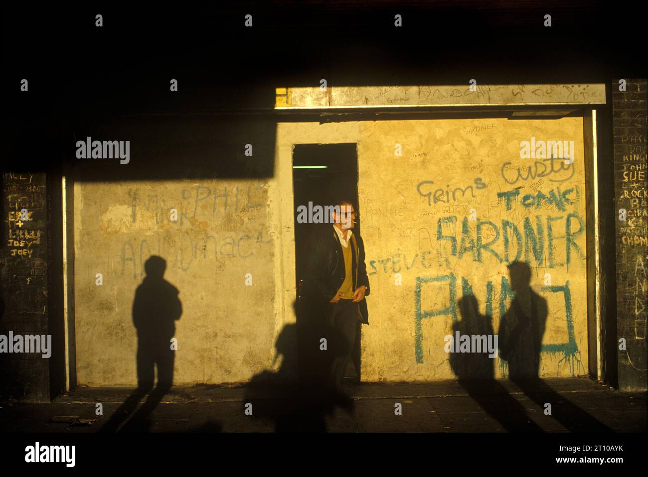 Crime, Poverty 1980s UK. Un negoziante d'angolo ha cementato la sua vetrina e ha lasciato solo una porta stretta che di notte è barricata con persiane d'acciaio. Serve le sue usanze da dietro una griglia metallica da pavimento a soffitto. Liverpool, Inghilterra 1981 HOMER SYKES Foto Stock
