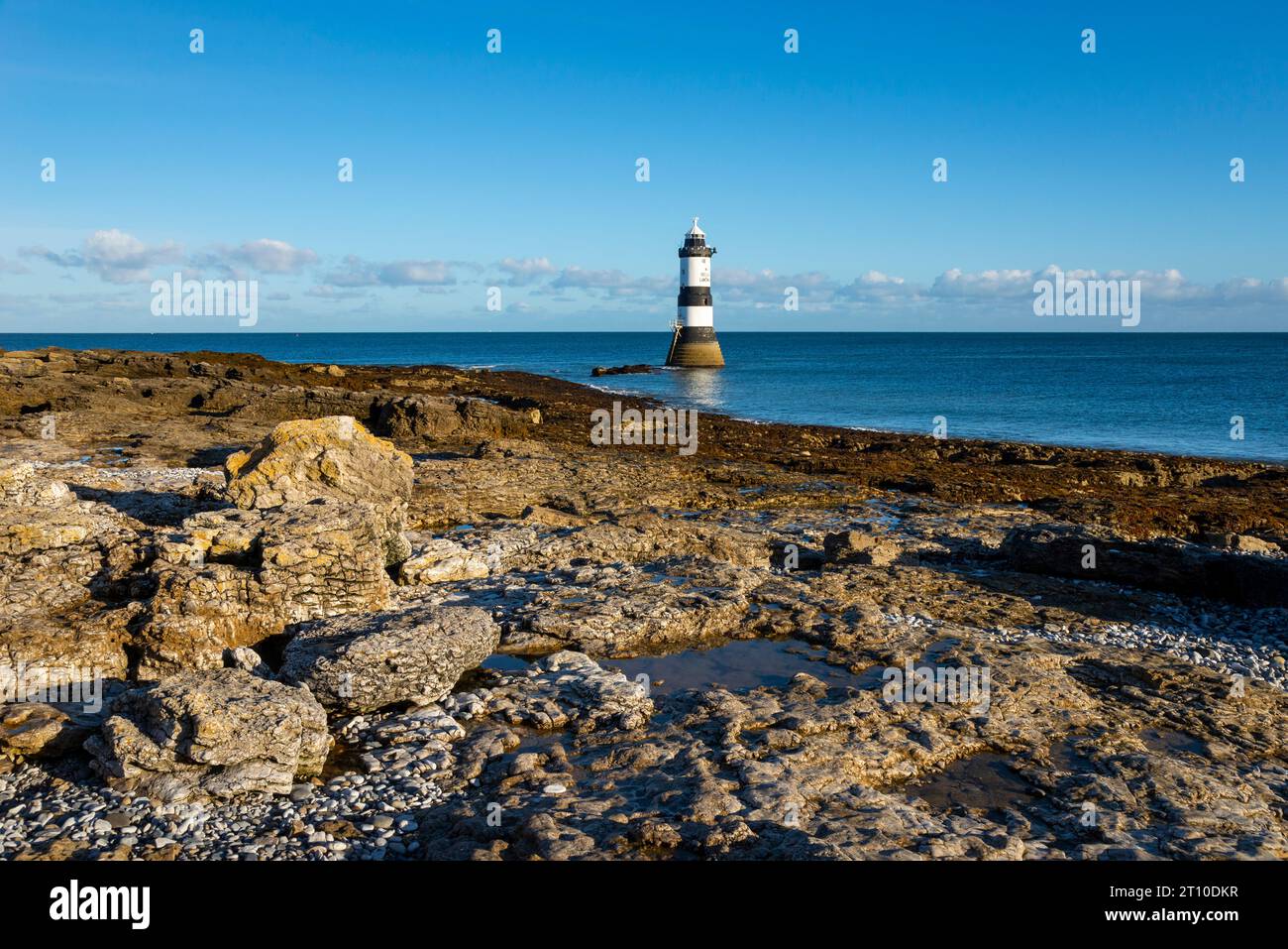 Penmon Point sulla costa di Anglesey, Galles del Nord. Il famoso faro di Trwyn Du alla luce del sole del mattino. Foto Stock