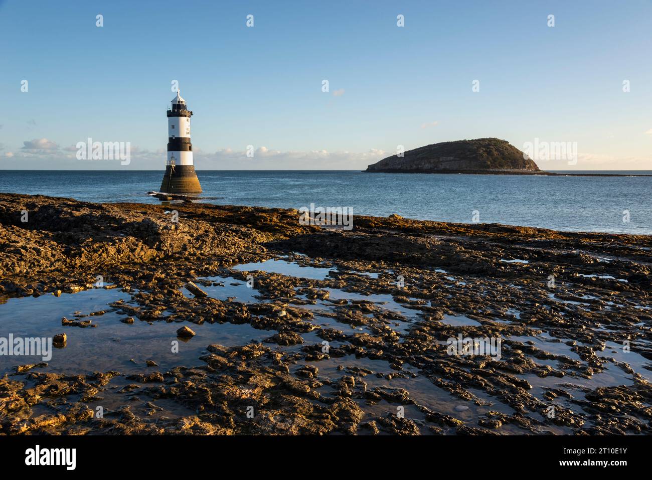 Penmon Point sulla costa di Anglesey, Galles del Nord. Faro di Trwyn Du con Puffin Island alle spalle. Foto Stock