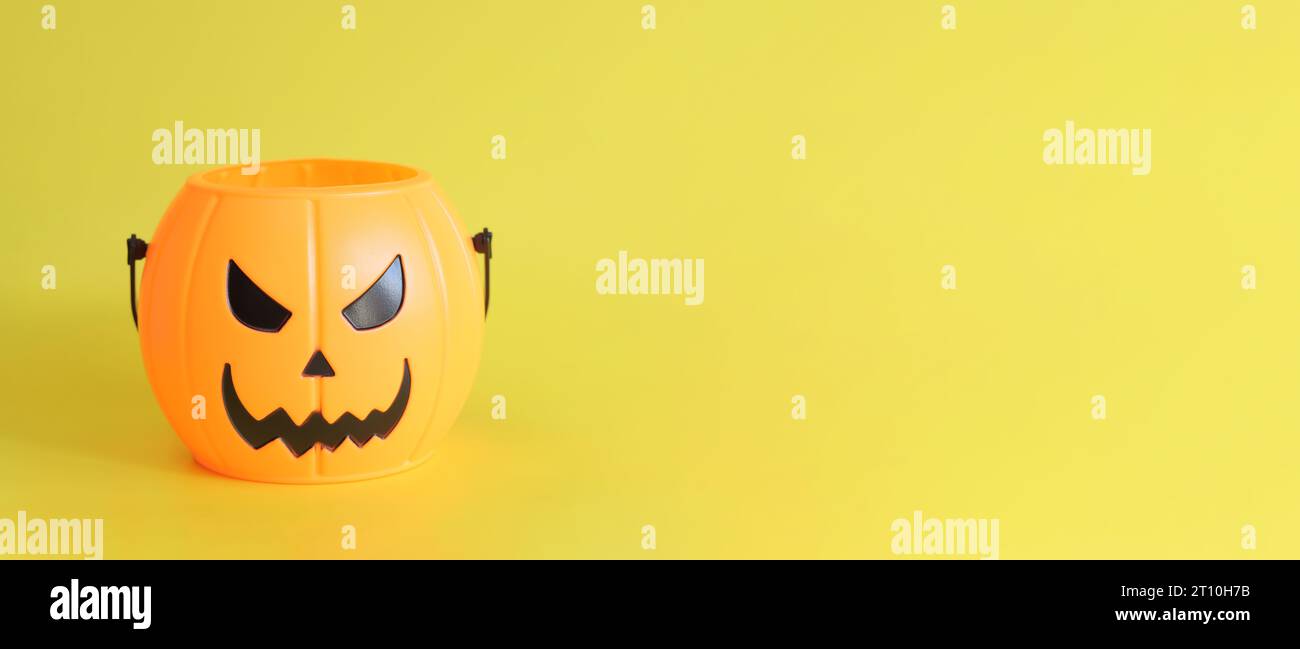 Buon Halloween. Secchio di zucca in plastica con un sorriso malvagio su sfondo giallo, spazio vuoto per il testo. Copia spazio. Banner per Halloween Foto Stock