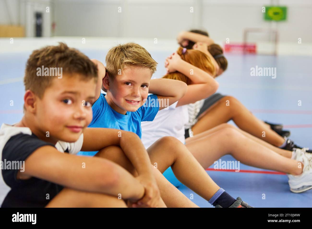 Ritratto di uno studente elementare che fa esercizio con gli amici durante le lezioni di ginnastica Foto Stock