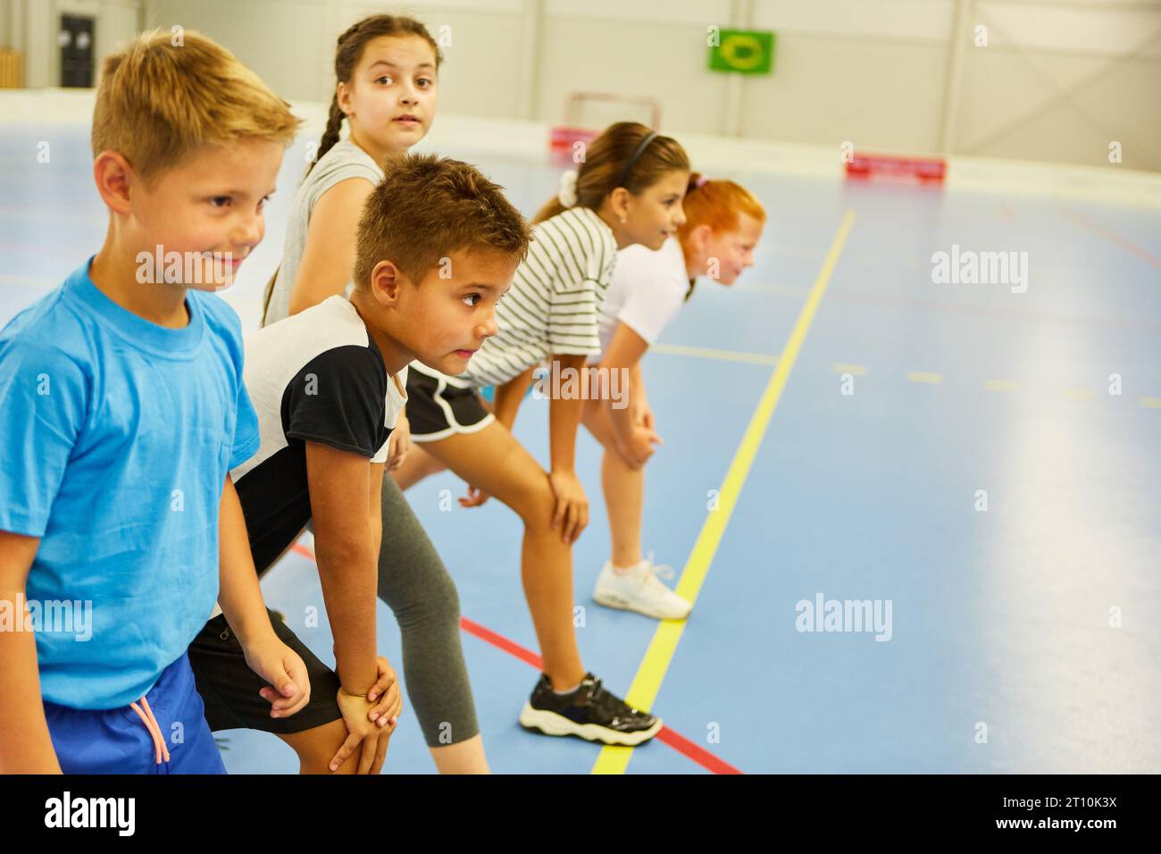 Studenti maschi e femmine determinati che si preparano per la corsa primaverile durante le lezioni di palestra Foto Stock