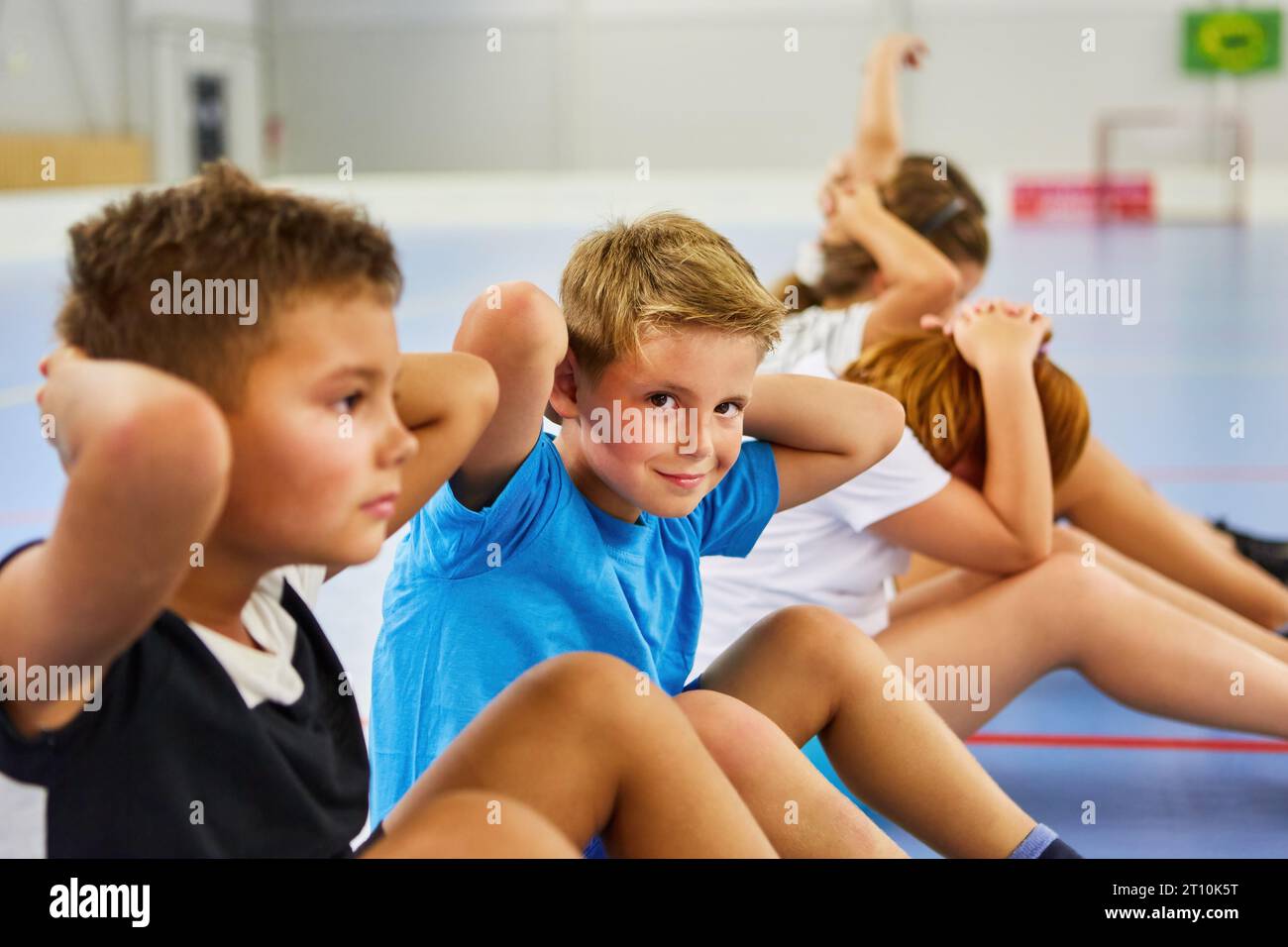 Gruppo di bambini felici che fanno sedute nella palestra della scuola elementare Foto Stock