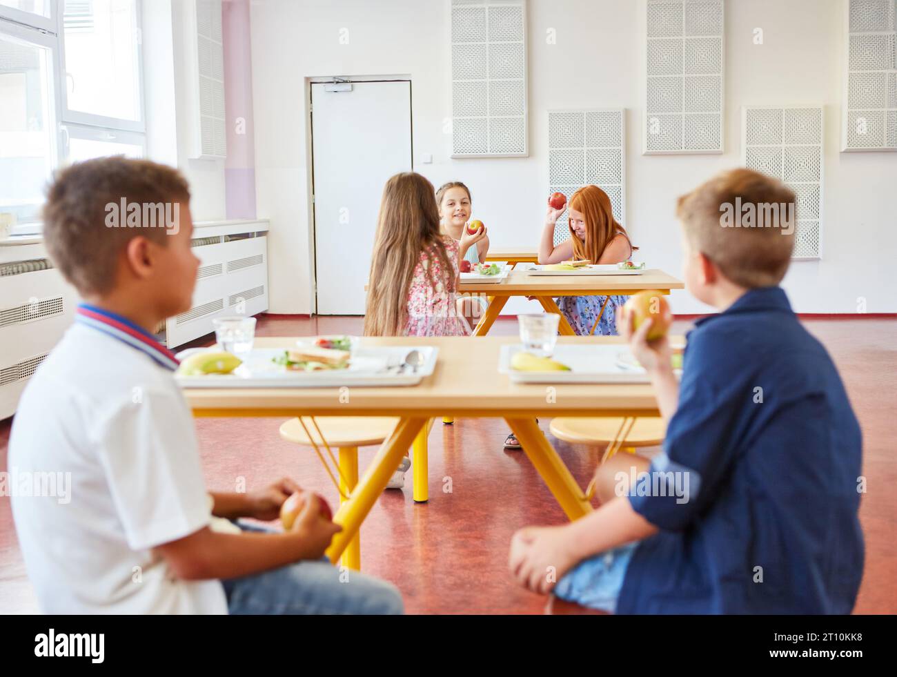 Gli studenti si divertono mangiando durante la pausa pranzo nella caffetteria scolastica Foto Stock