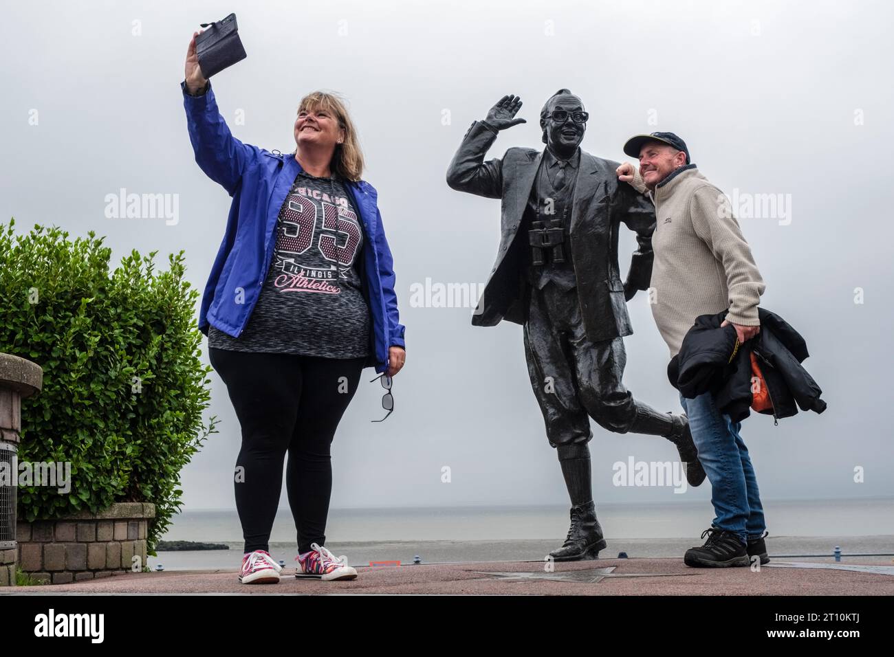 Turisti che scattano fotografie della statua di Eric Morecambe sul lungomare di Morecambe, Lancashire Foto Stock