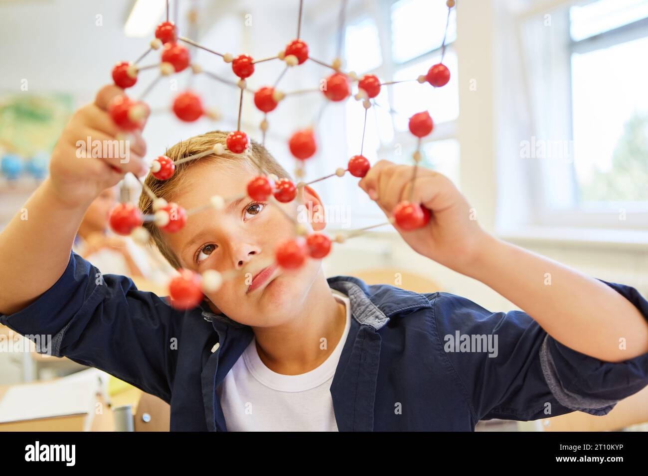 Studente elementare che analizza la struttura molecolare in classe a scuola Foto Stock