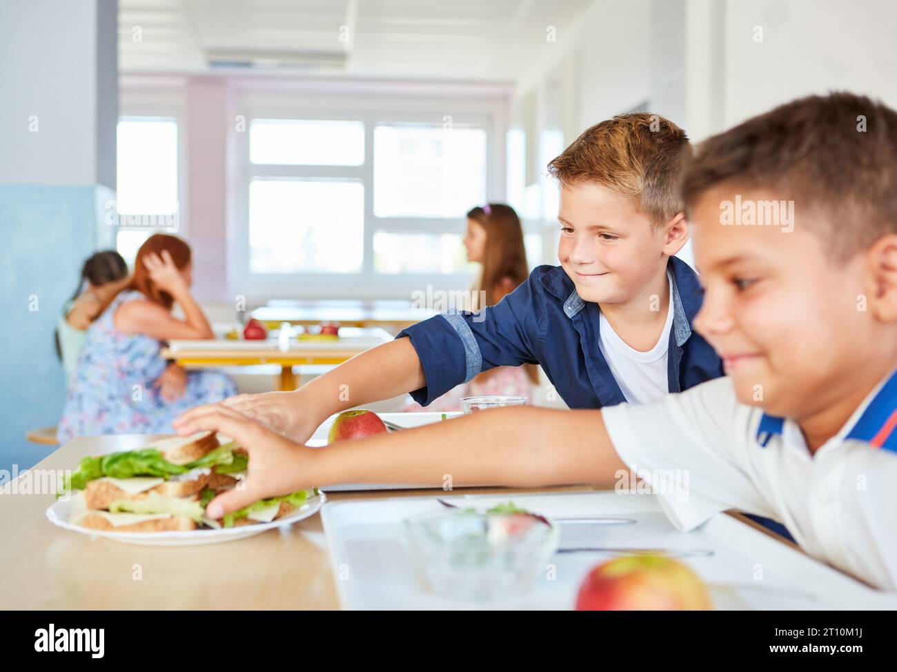 Sorridenti studenti maschi che prendono panini freschi durante il pranzo a scuola alla caffetteria Foto Stock