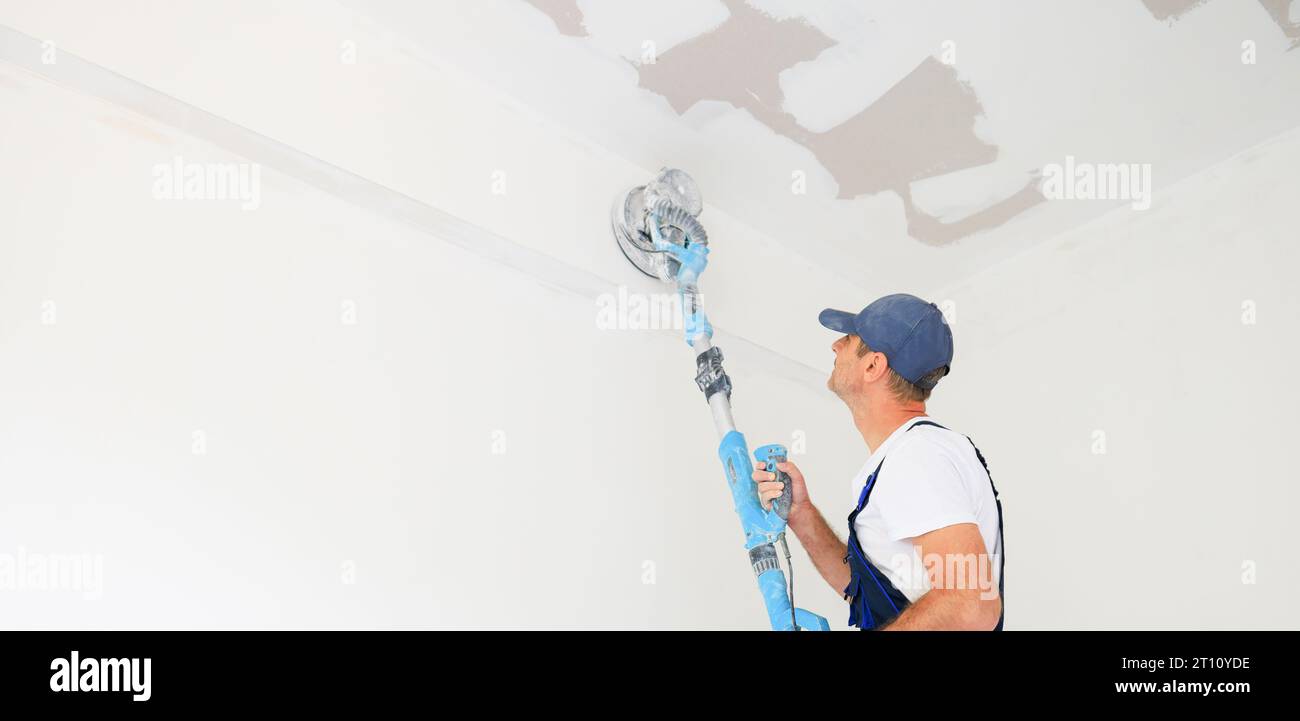 Pittore domestico professionale che utilizza una levigatrice per pareti per lucidare superfici. Foto Stock