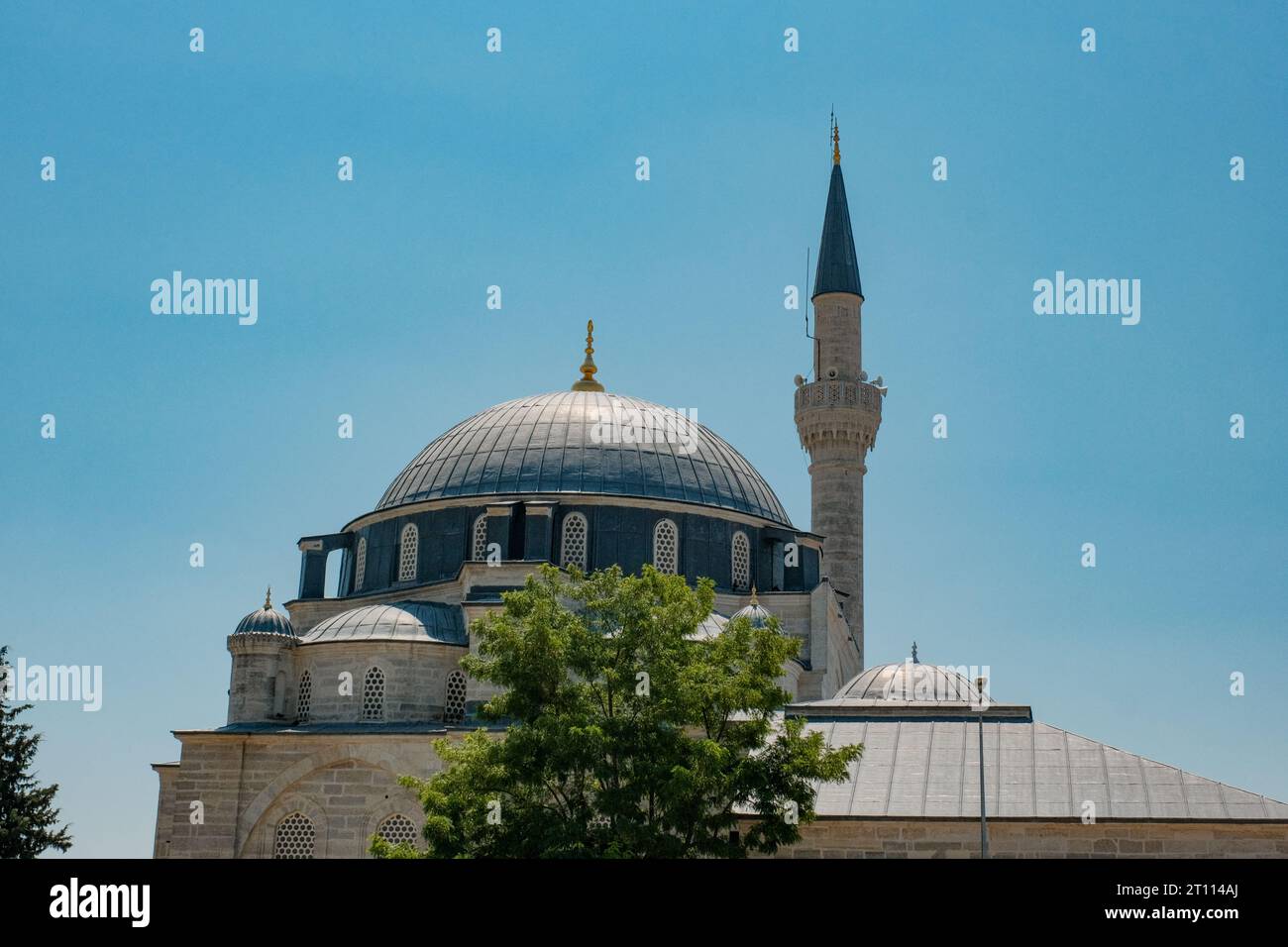 I contorni aggraziati di una tradizionale moschea turca contrastano delicatamente il cielo azzurro, circondato da un'atmosfera serena. Foto Stock