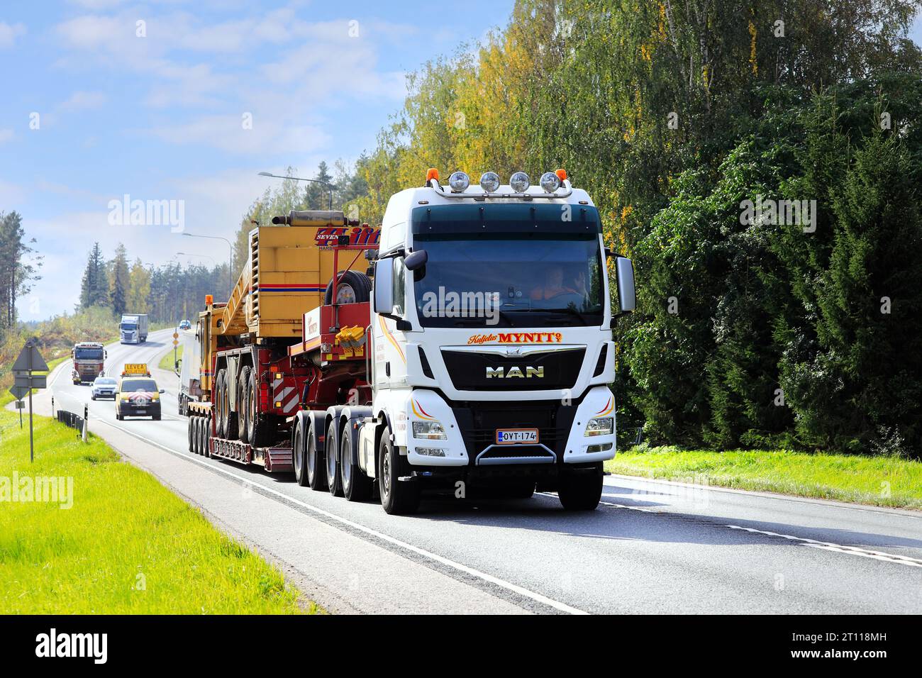 L'autocarro MAN TGX 33,580 trasporta la gru SevenLift su un rimorchio con pianale ribassato come segue un'auto di scorta di grandi dimensioni. Raasepori, Finlandia. 22 settembre 2023. Foto Stock