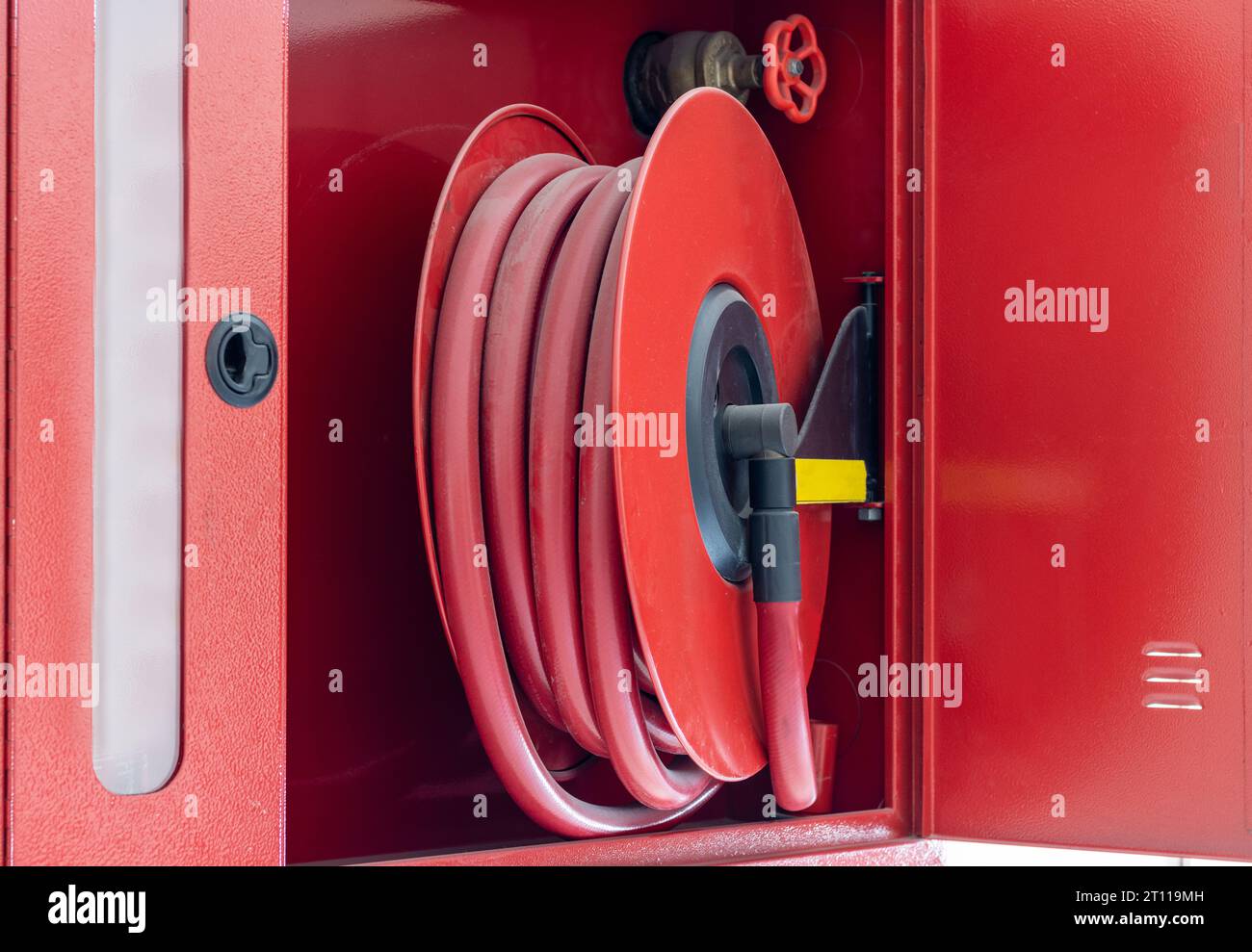 Tubo dell'acqua rosso dell'estintore sulla parete. Impianto antincendio di edifici Foto Stock