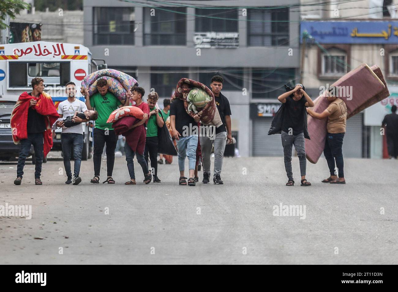 Gaza City, territori palestinesi. 10 ottobre 2023. Donne e bambini palestinesi camminano per strada portando i loro materassi, cercando rifugio dagli attacchi aerei israeliani. Credito: Mohammed Talatene/dpa/Alamy Live News Foto Stock