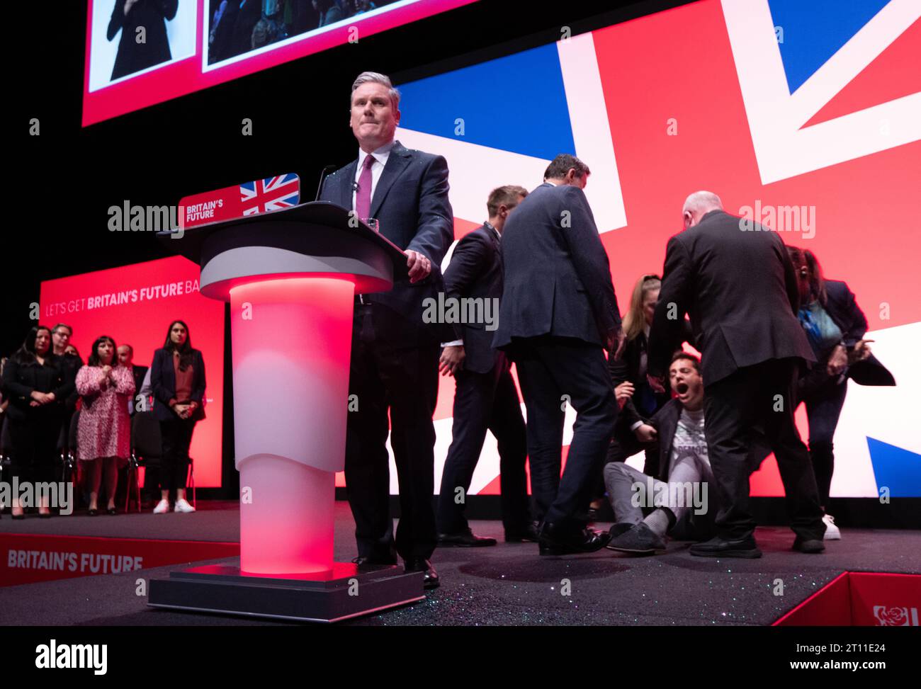 Liverpool, Regno Unito. 10 ottobre 2023. Il manifestante copre Keir Starmer con glitter durante l'inizio del discorso dei leader. Il manifestante è stato combattuto a terra e rimosso dalla sicurezza. Sir Keir si spazzolò i capelli si tolse la giacca e proseguì col discorso. Conferenza del lavoro 2023. Foto: Garyroberts/worldwidefeatures.com credito: GaryRobertsphotography/Alamy Live News Foto Stock