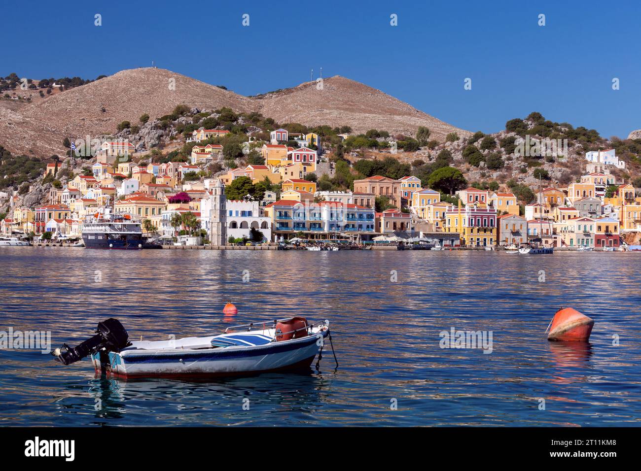 Case tradizionali colorate nel villaggio greco di Symi sulla riva di una baia in una giornata di sole. Grecia. Foto Stock