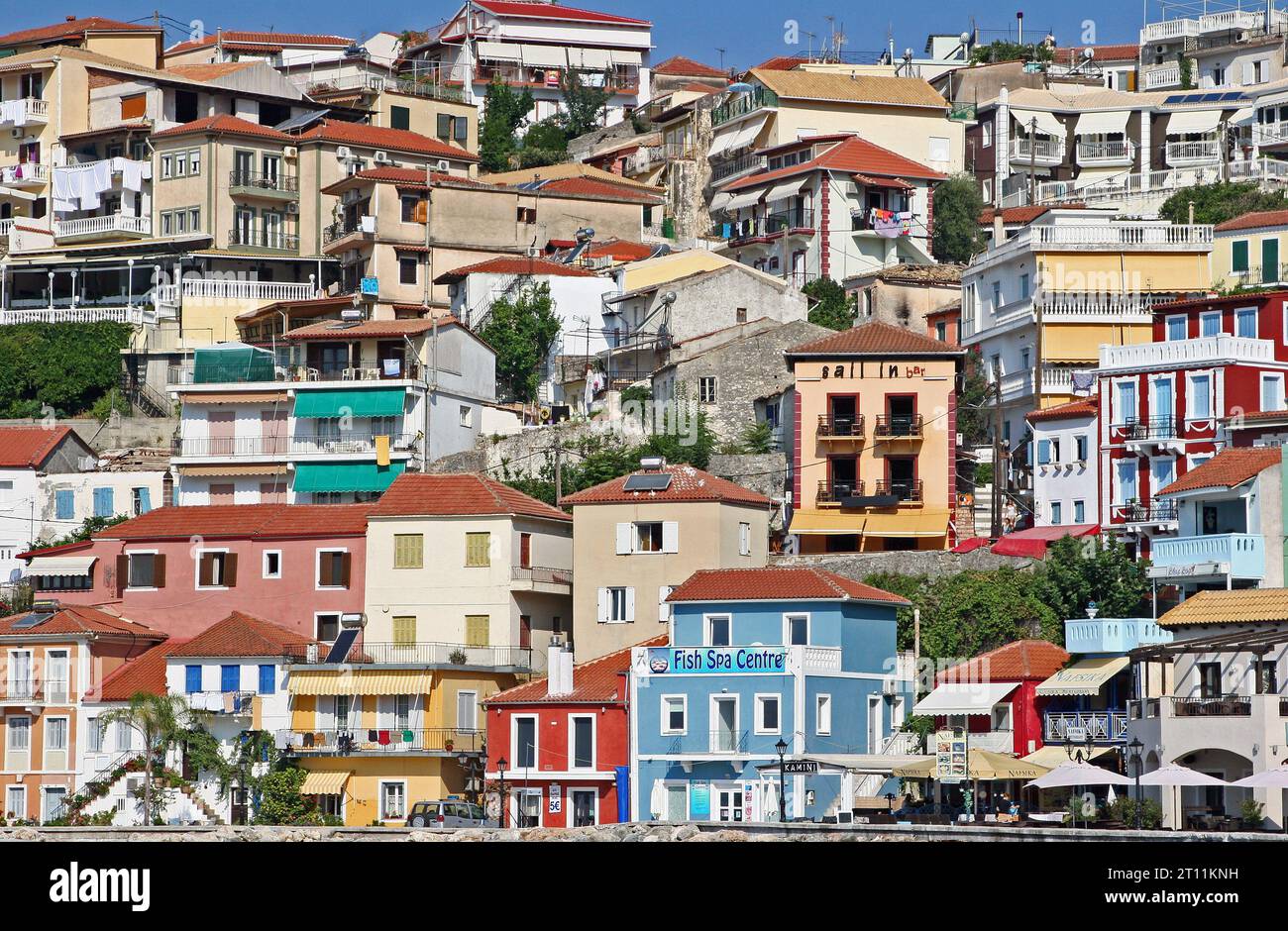 Colorate case e ristoranti sulla scogliera si affacciano sul pittoresco lungomare di Parga, una cittadina costiera nella regione dell'Epiro, nel nord-ovest della Grecia continentale Foto Stock